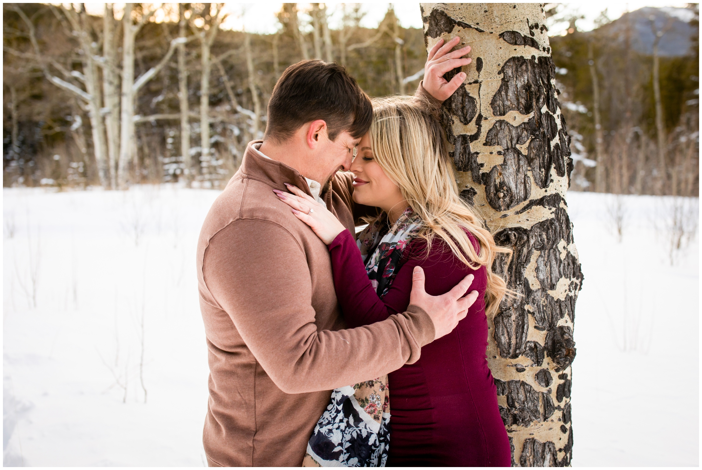 couple leaning against an aspen tree in the snow in Evergreen CO