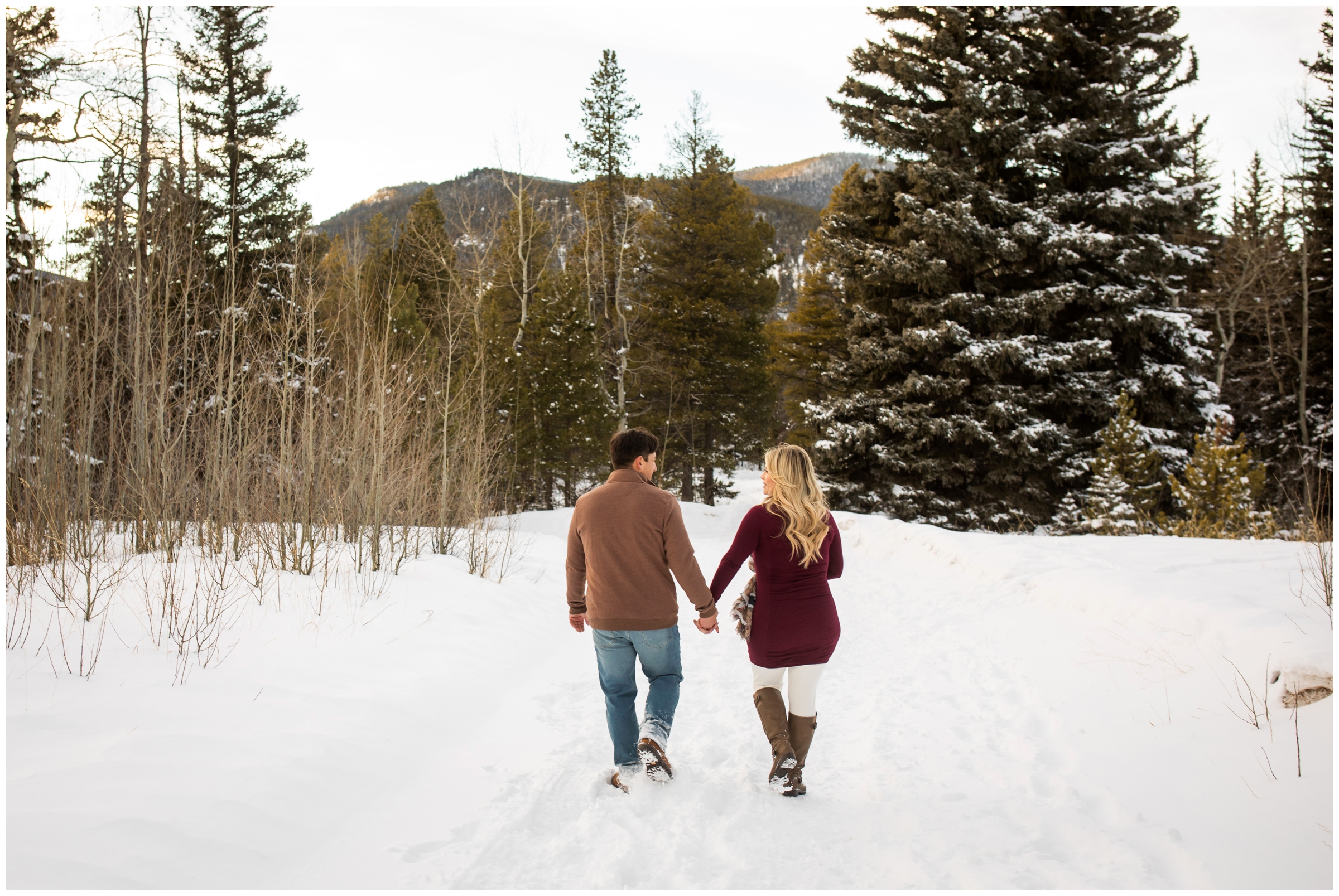 couple holding hands and walking through the snow during Evergreen Colorado engagement photos 