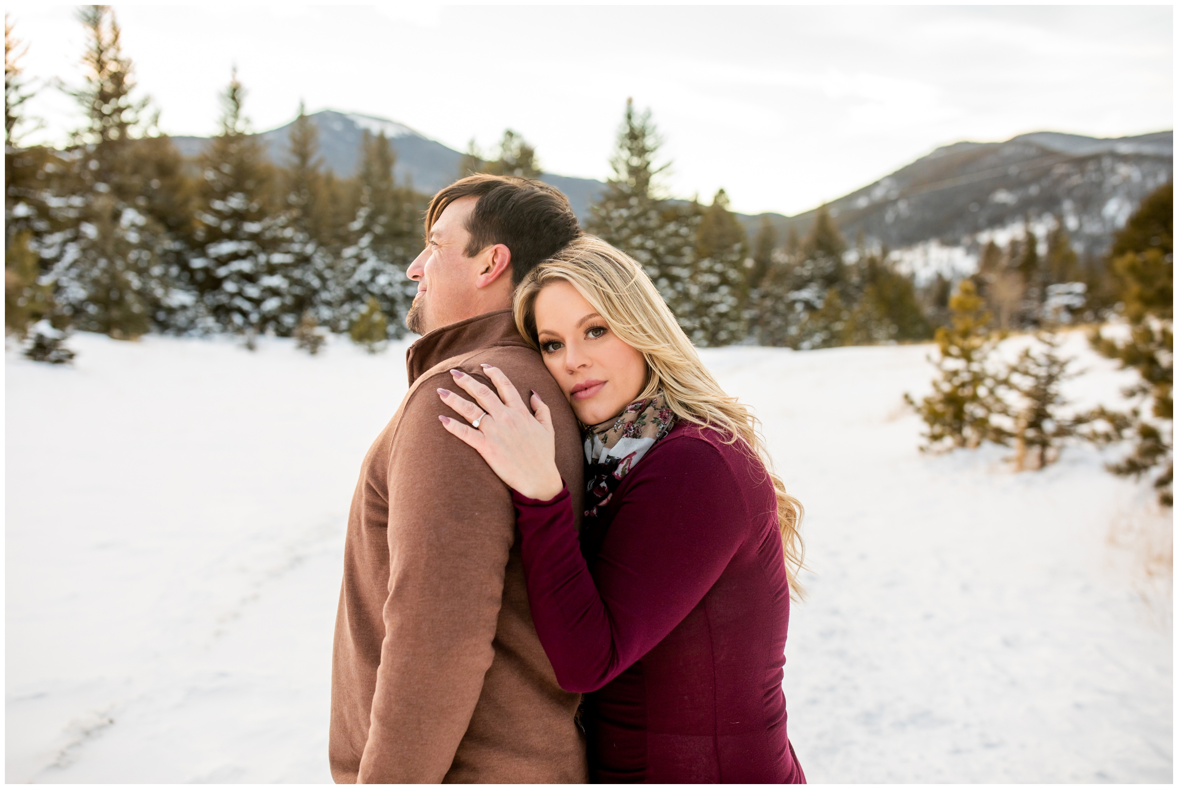 couple cuddling in the snow during winter engagement portraits in the Colorado mountains 