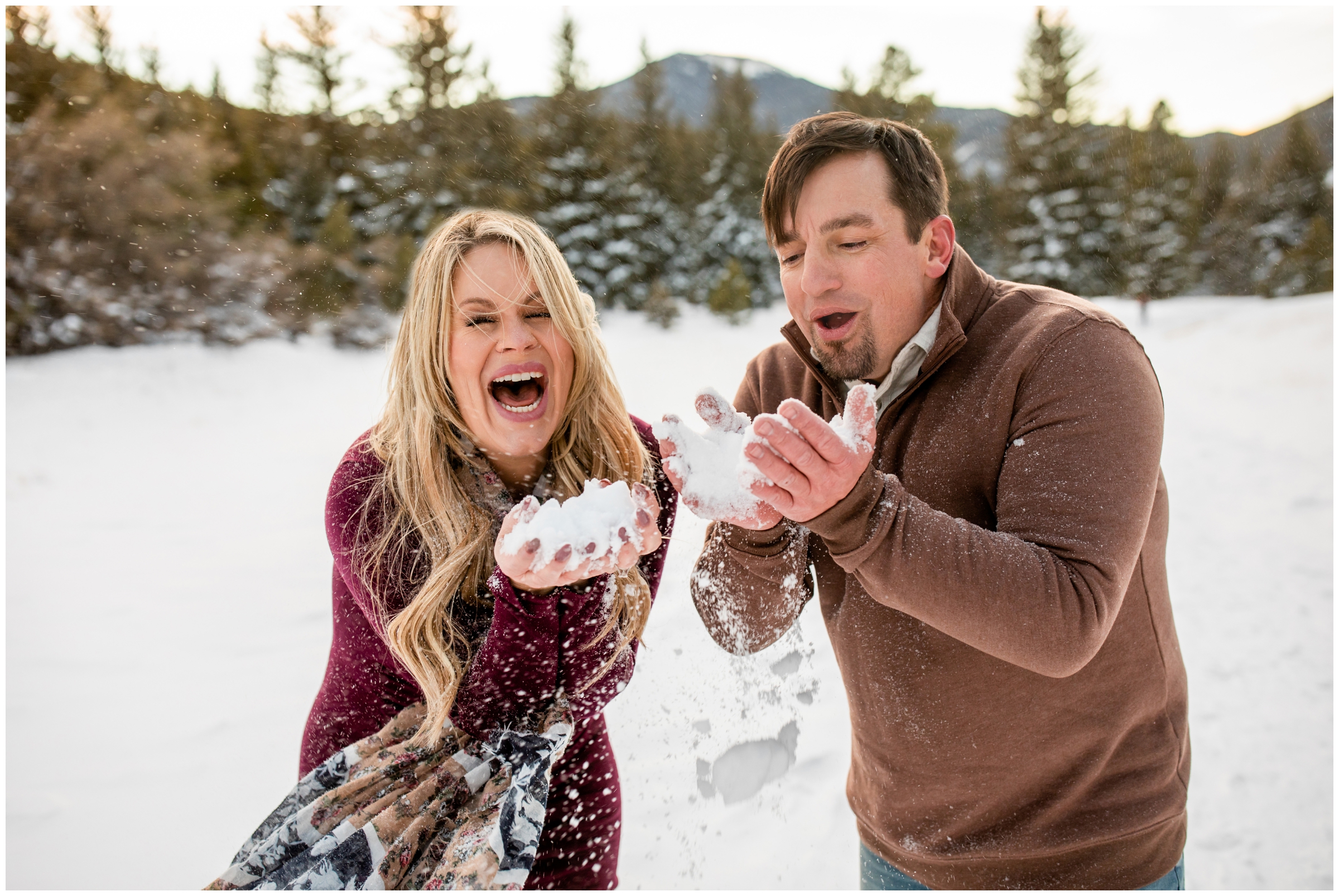 couple blowing snow at the camera during photo session by Evergreen CO photographer Plum Pretty Photography