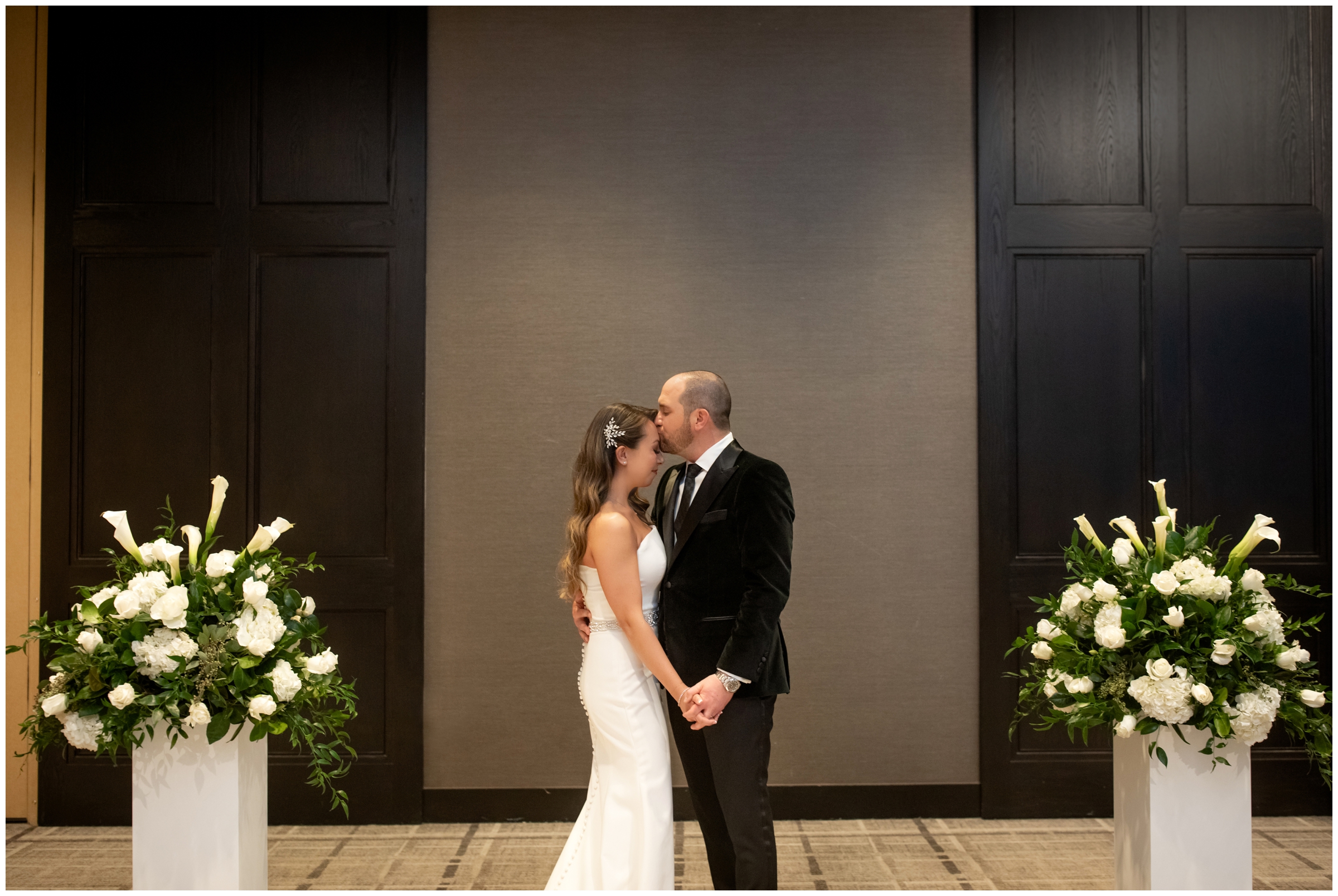 groom kissing bride's forehead during indoor winter wedding pictures in Cherry Creek area of Denver Colorado 