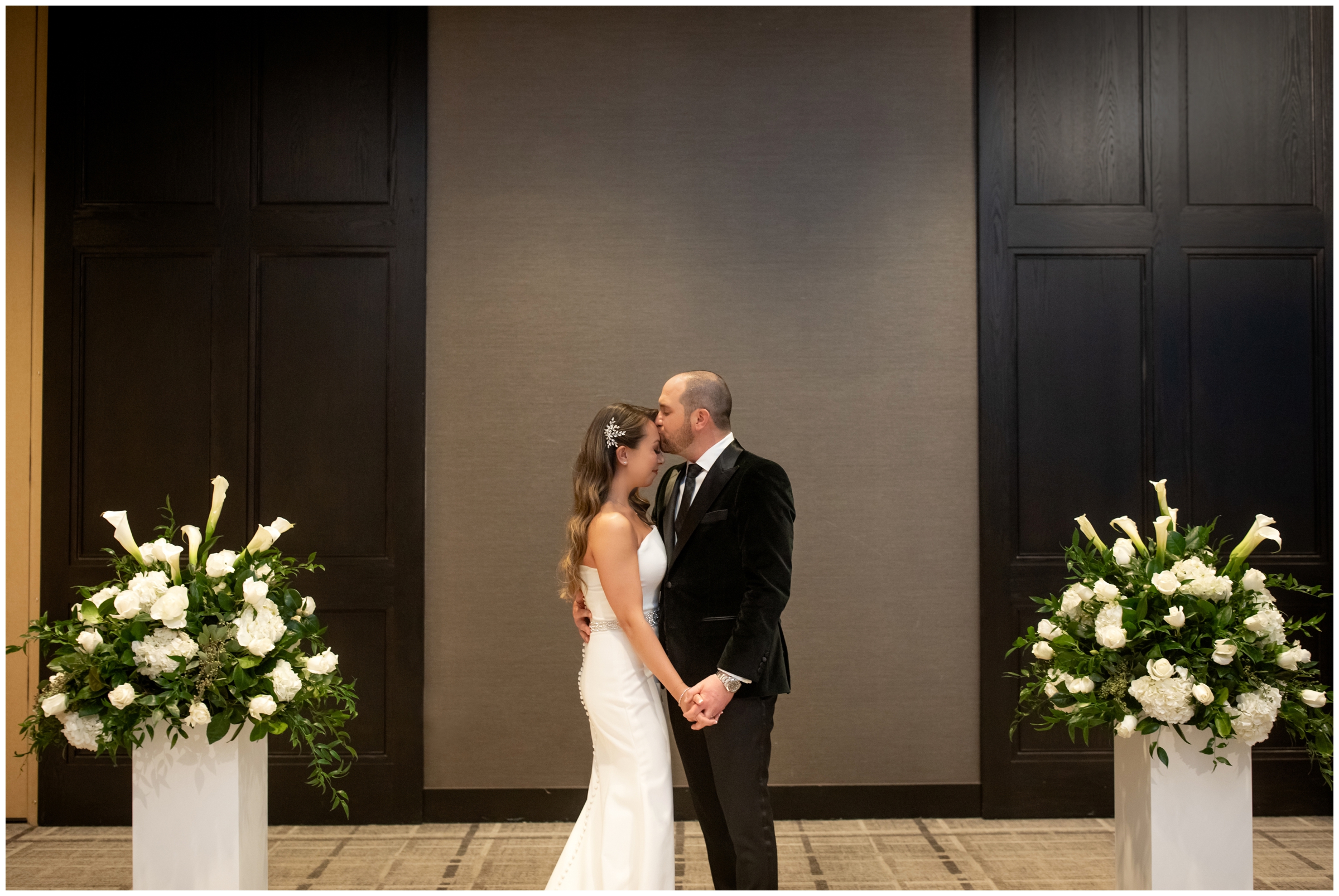 groom kissing bride's forehead during indoor winter wedding pictures in Cherry Creek area of Denver Colorado