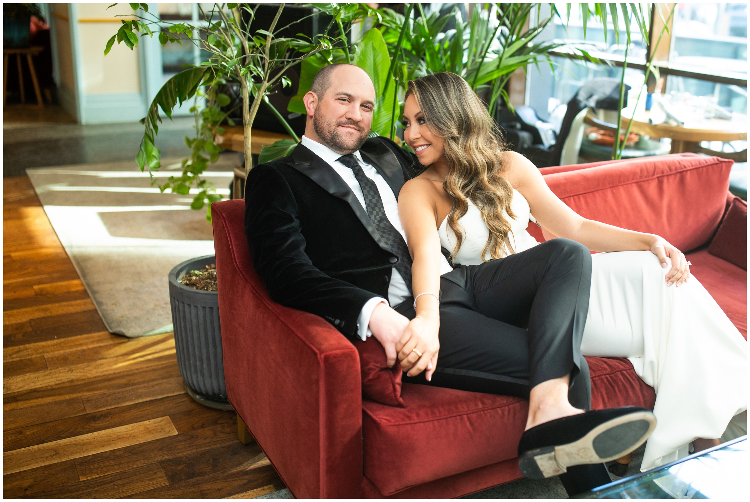bride and groom posing on red couch in bar area at the Halcyon Hotel in Cherry Creek Colorado 