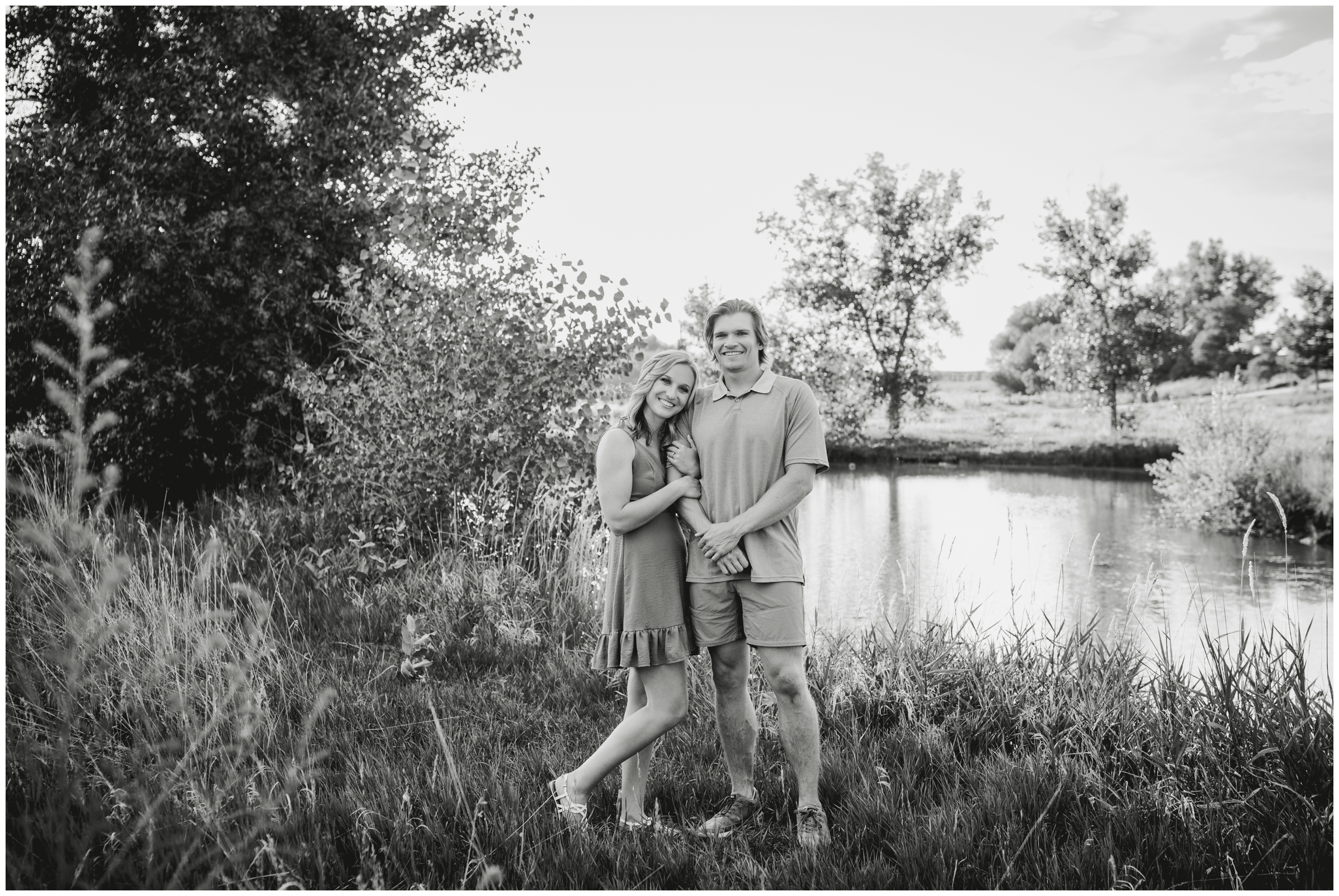 couple cuddling next to a pond during Colorado summer engagement pictures in Longmont 