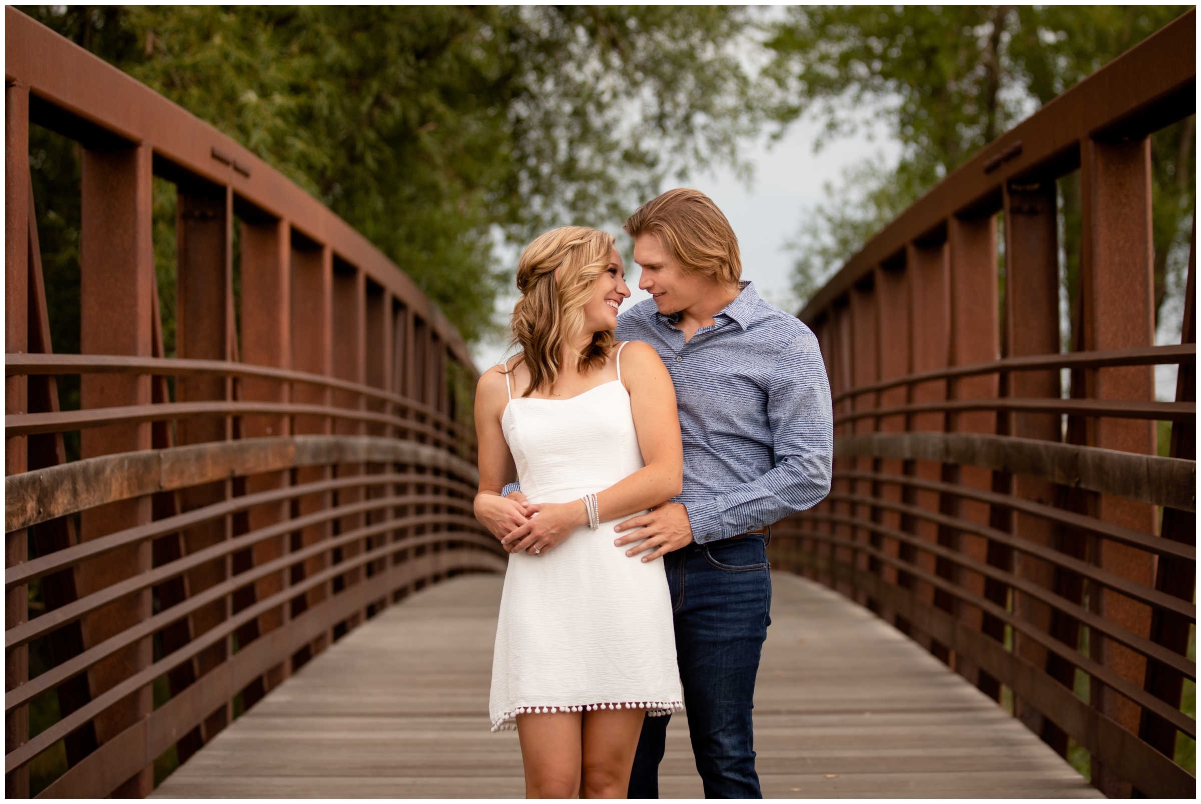 couple cuddling on a bridge during Longmont engagement portraits at Sandstone Ranch 