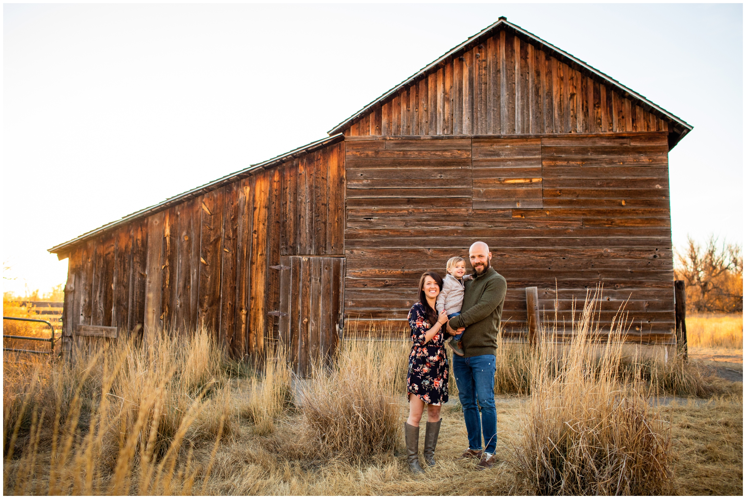 family of three posing in front of rustic barn during fall family photography session in Longmont Colorado 