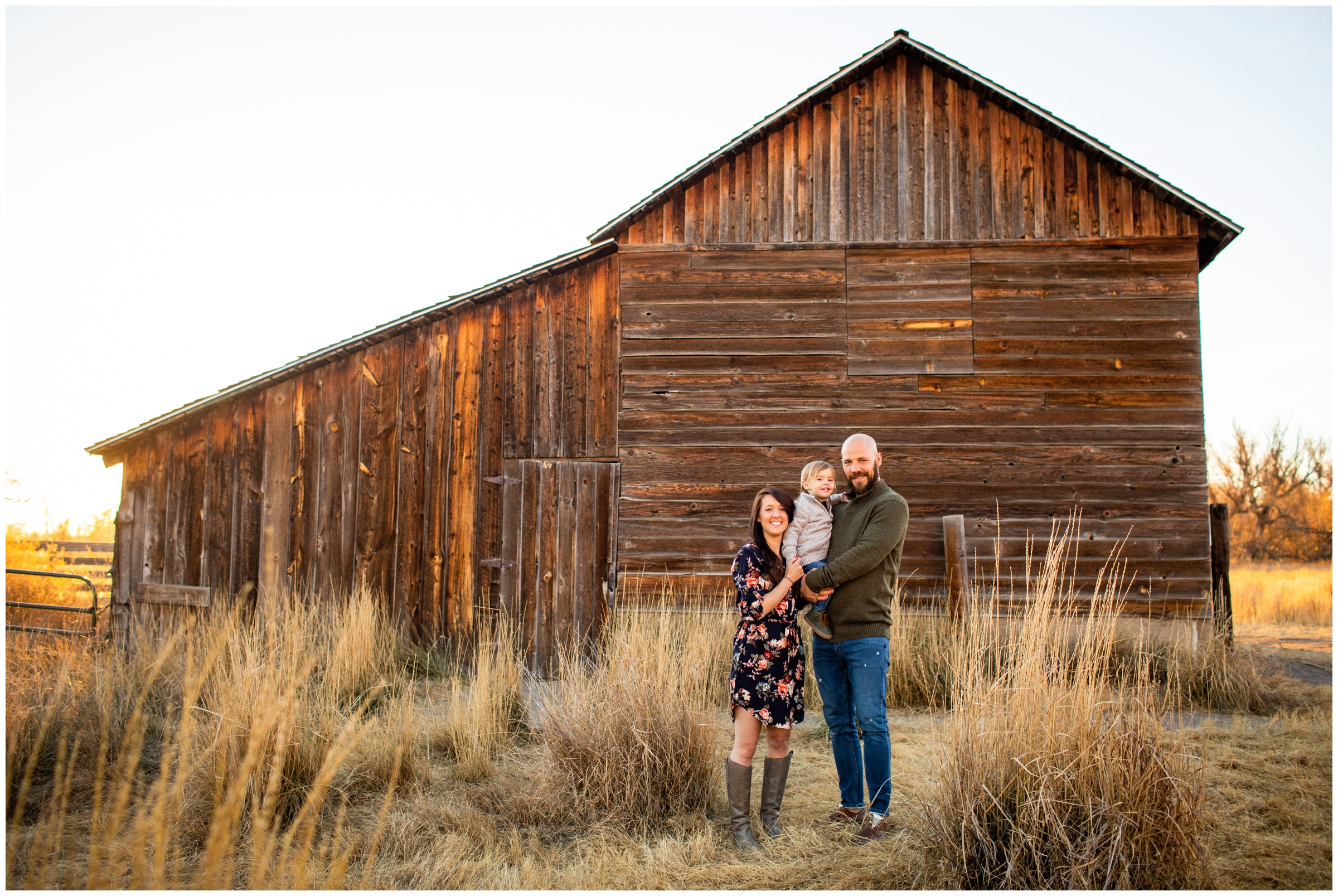 family of three posing in front of rustic barn during fall family photography session in Longmont Colorado