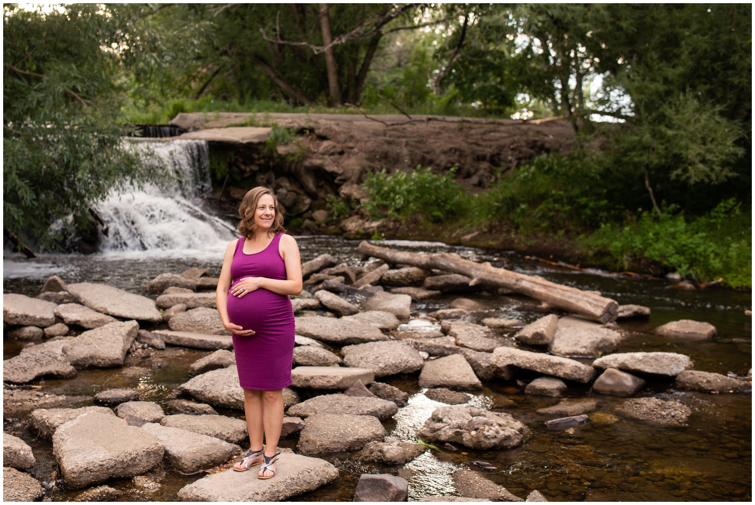 pregnant woman posing on rocks with waterfall in background during Longmont maternity photography session at golden Ponds
