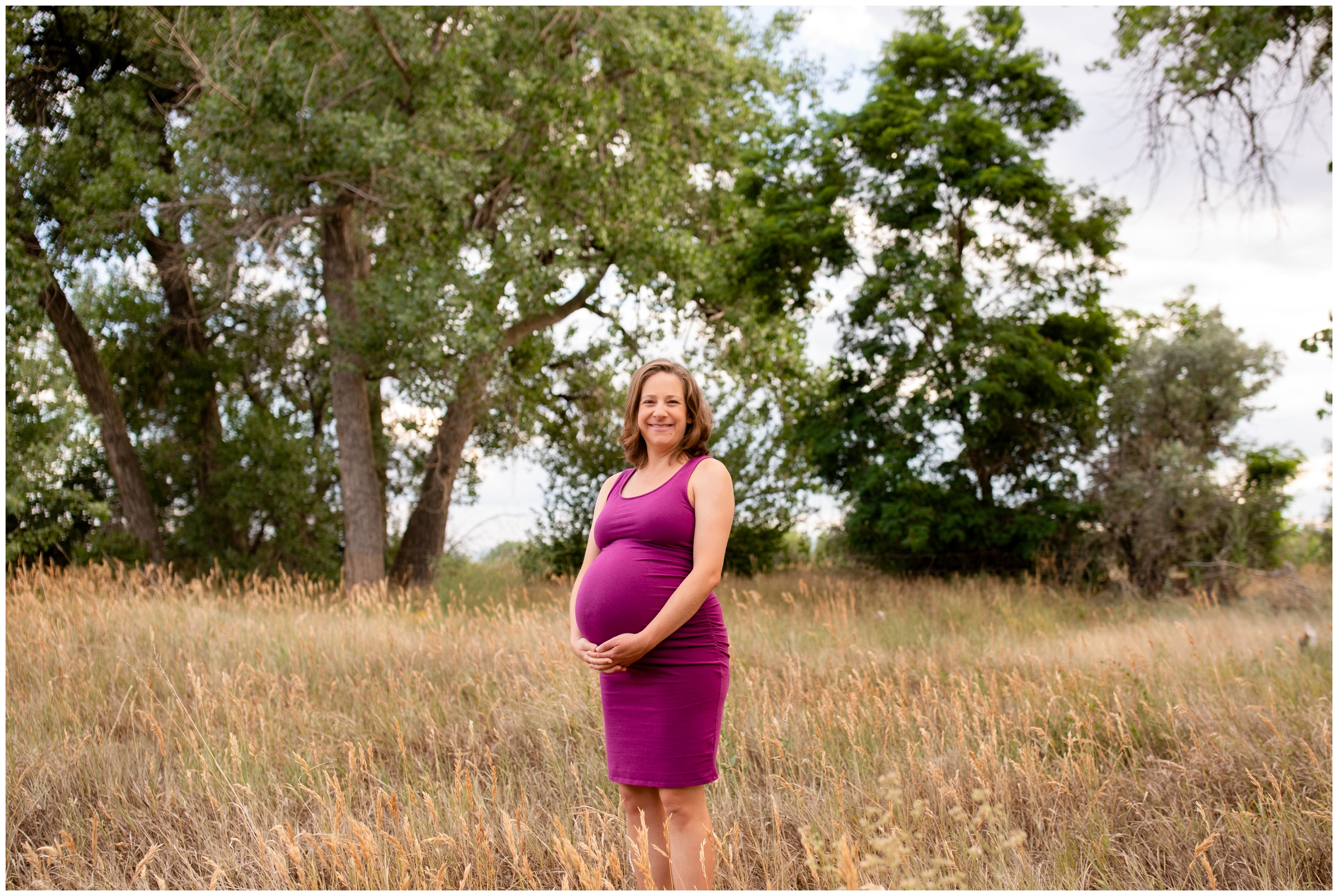 woman posing in field of long grasses during Colorado summer maternity portraits 