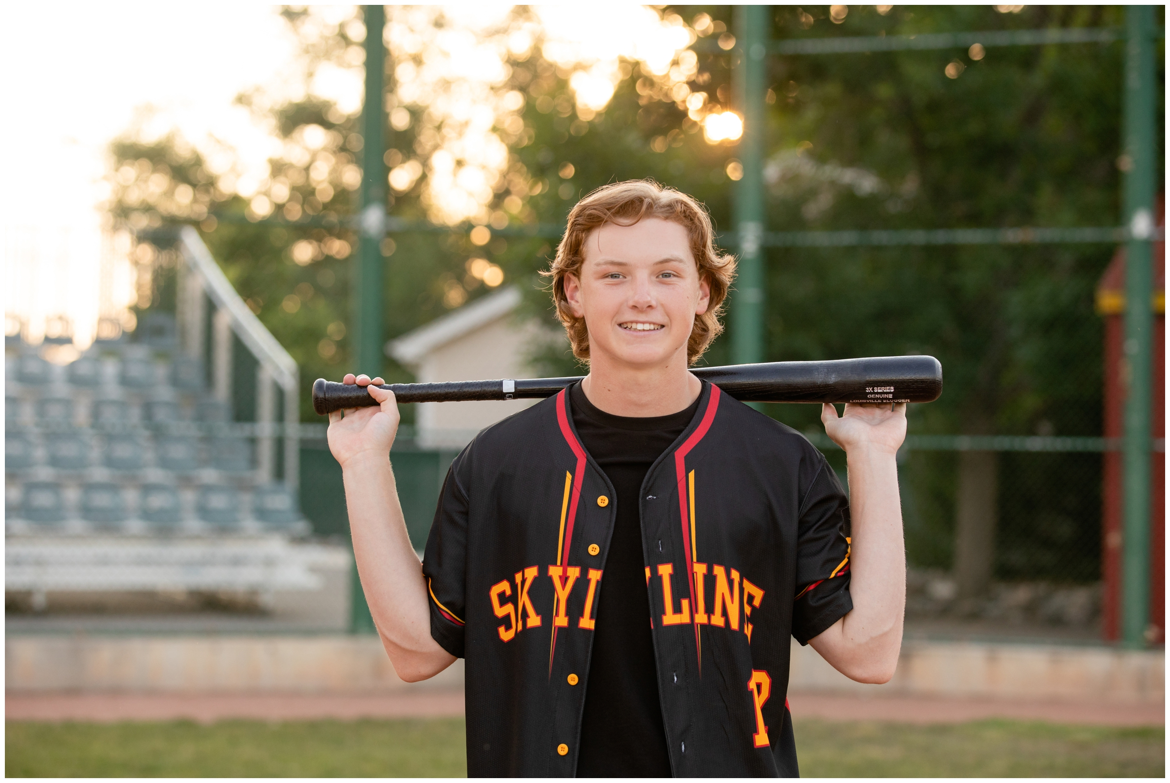 teen guy with bat over shoulders during baseball senior pictures at Skyline High in Colorado 