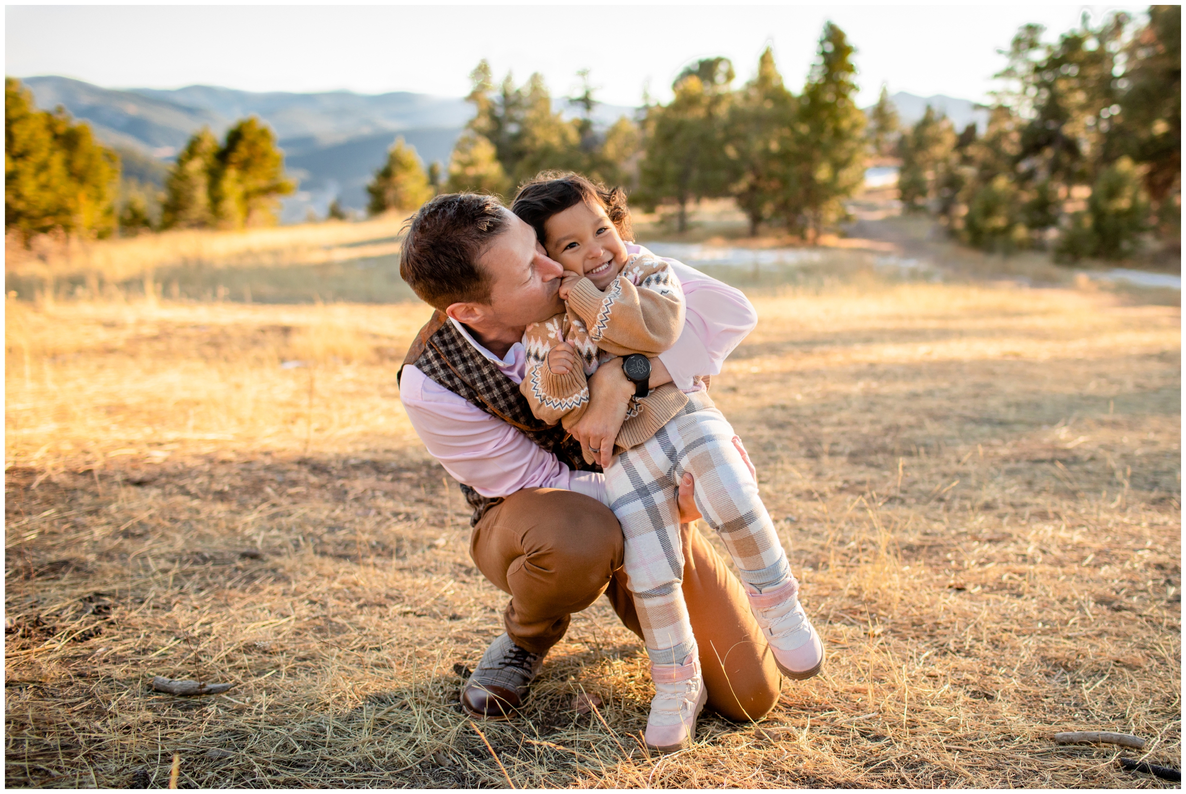 dad kissing daughter during winter family photos at Mount Falcon west in Colorado 