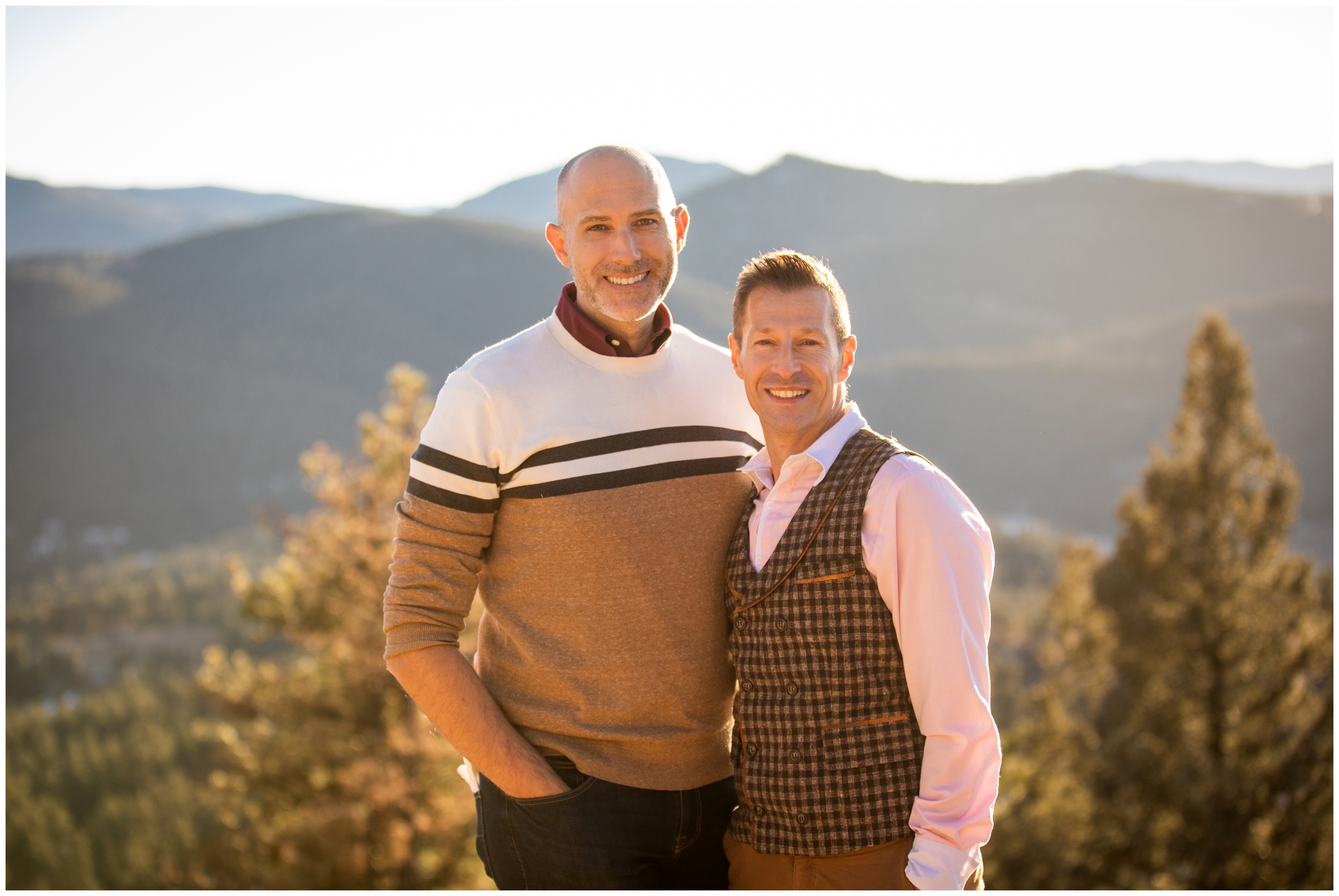 gay couple smiling with mountains in background during Colorado winter couple's photos 
