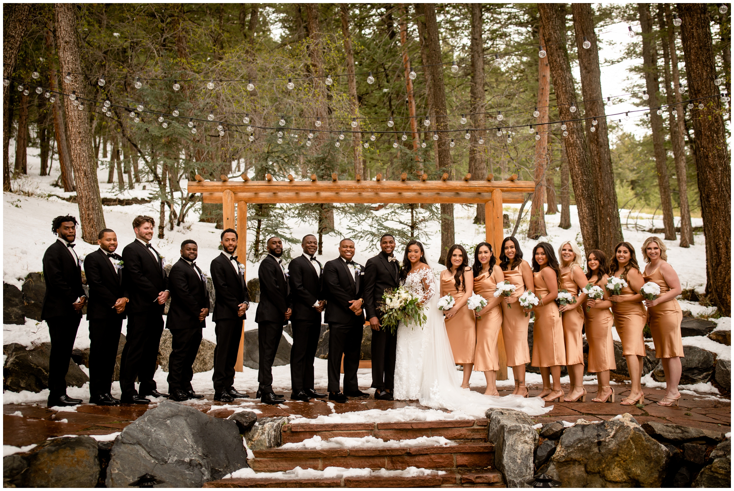 wedding party in gold and black posing under market lights at Colorado winter wedding