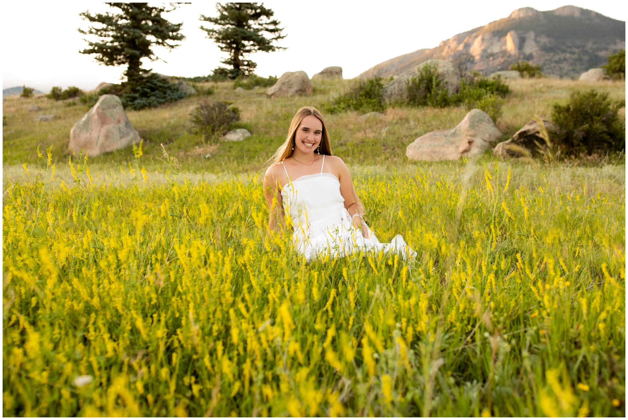 teen sitting in wildflower field during Colorado mountain senior photos in RMNP