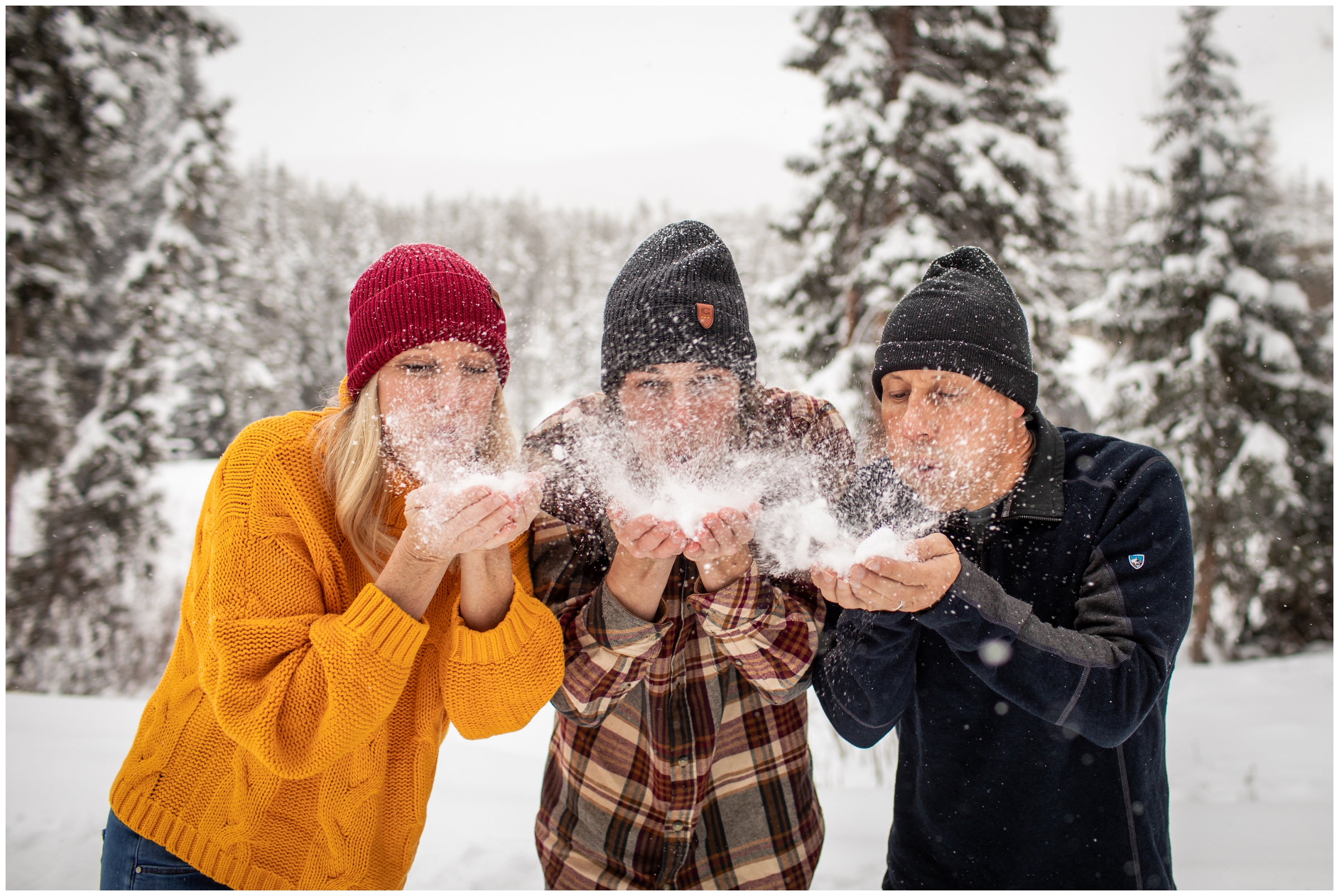 family blowing snow at camera during candid winter family photo session in Winter Park Colorado 