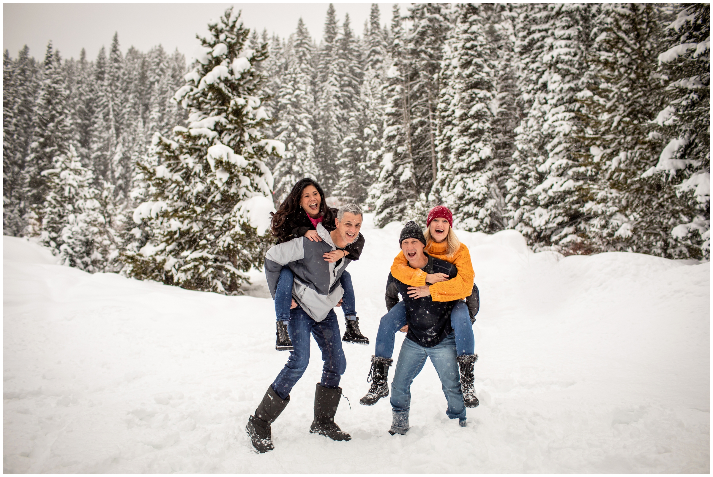 parents giving piggy back rides during candid snowy Winter Park family photos by Plum Pretty Photography 