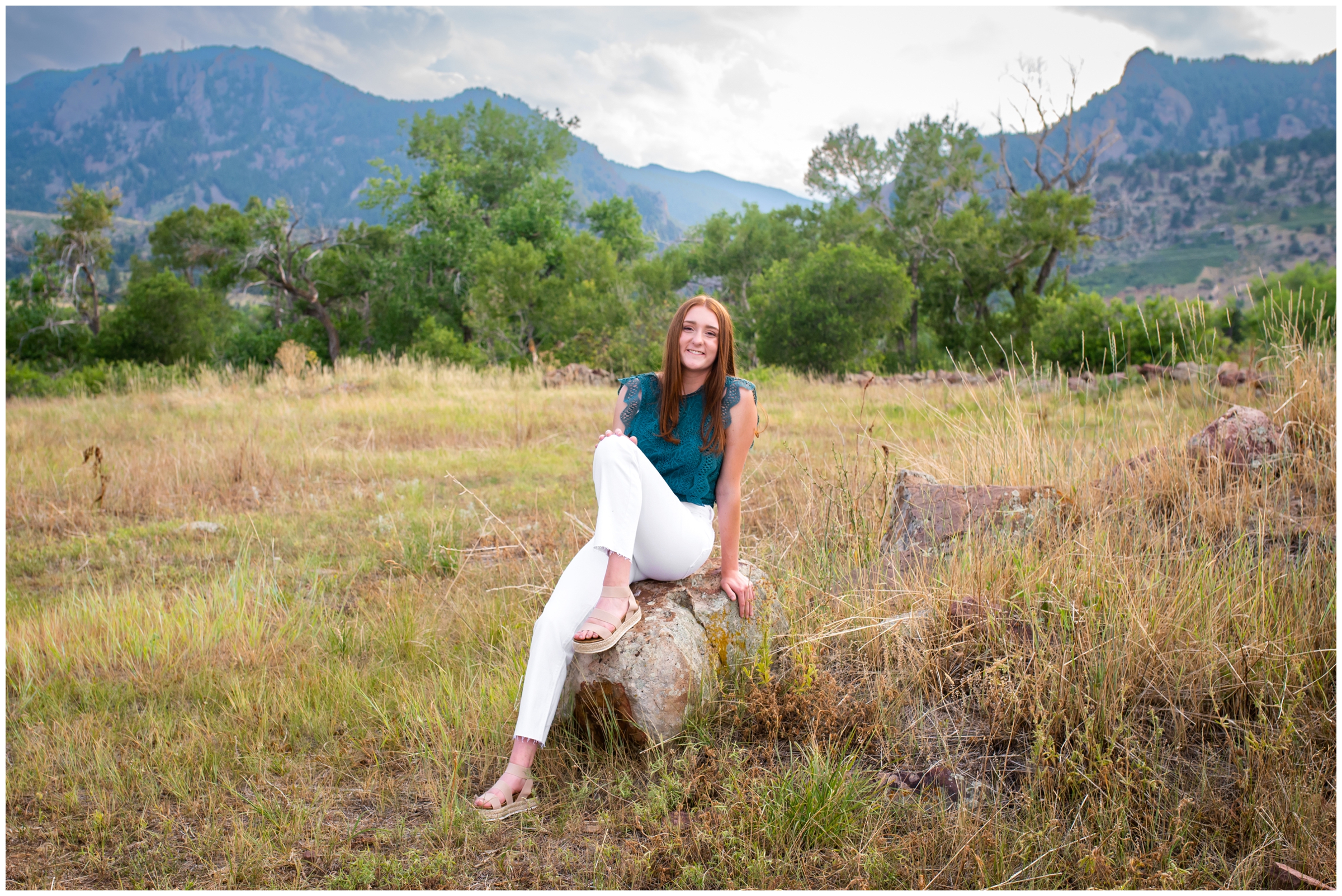teen posing on a rock with mountains in the background during Boulder senior pictures at South Mesa Trail