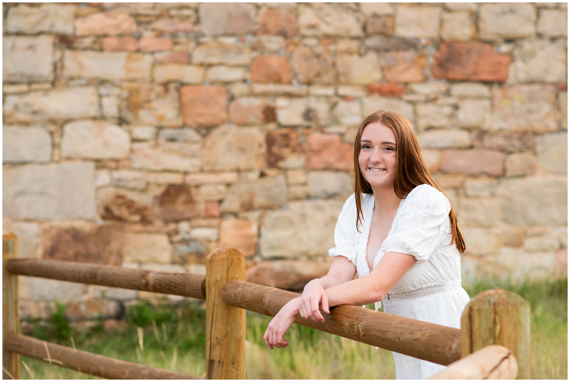 teen leaning on a wooden fence with stone wall in background during Colorado graduation photos 