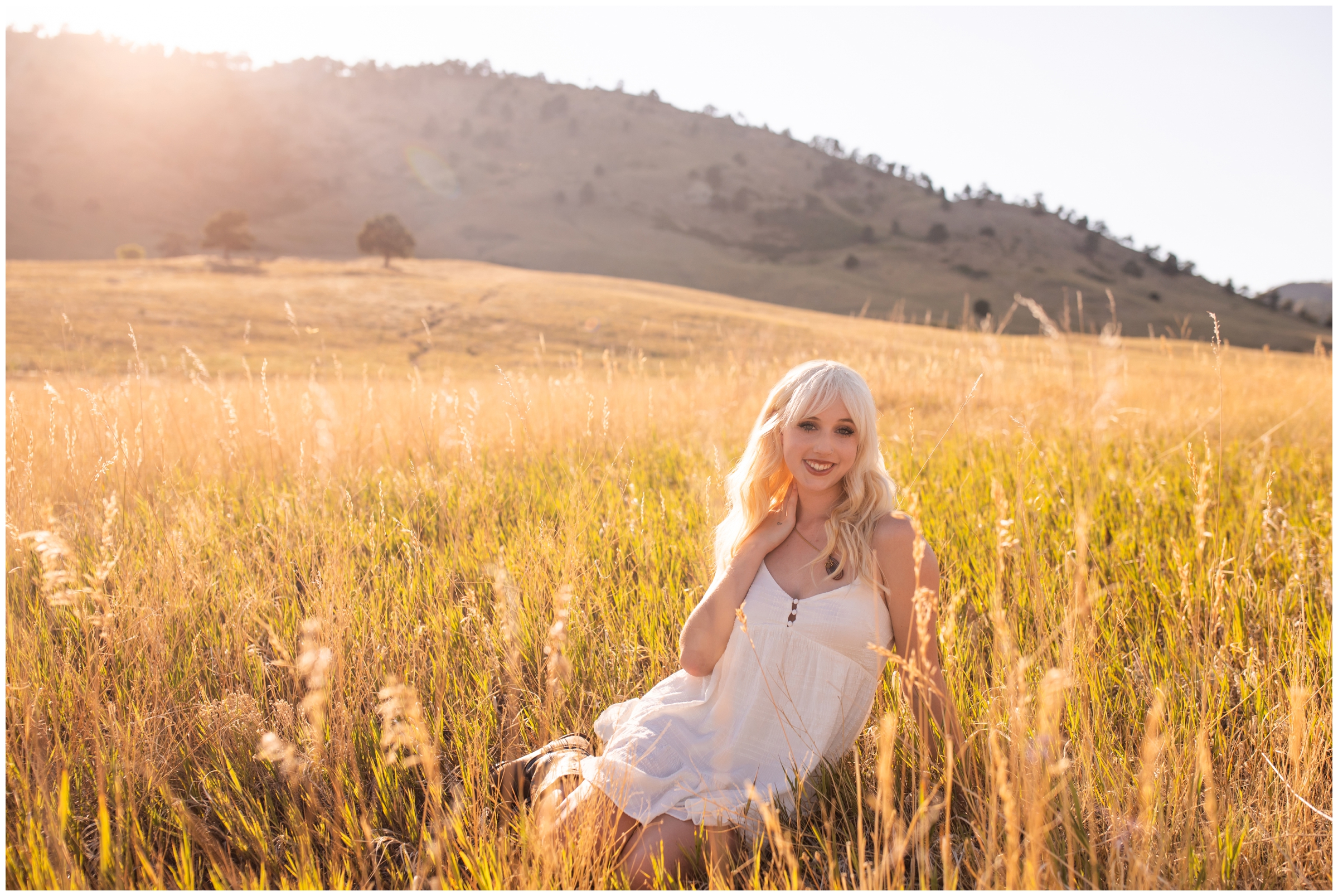 teen sitting in field of long grasses during Boulder Colorado senior pictures 