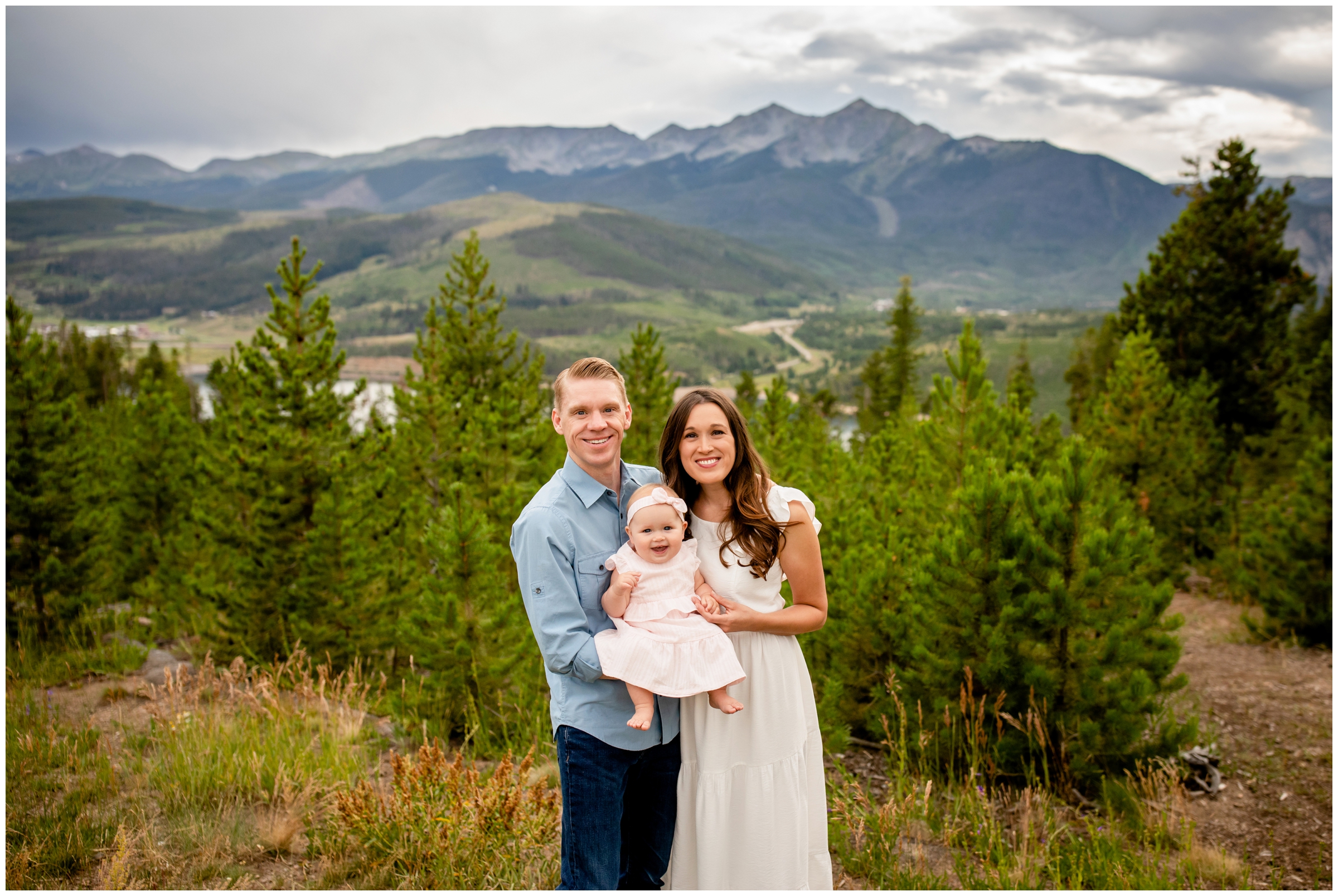 adorable family of three posing with mountains in background during Summit County Colorado photography session  