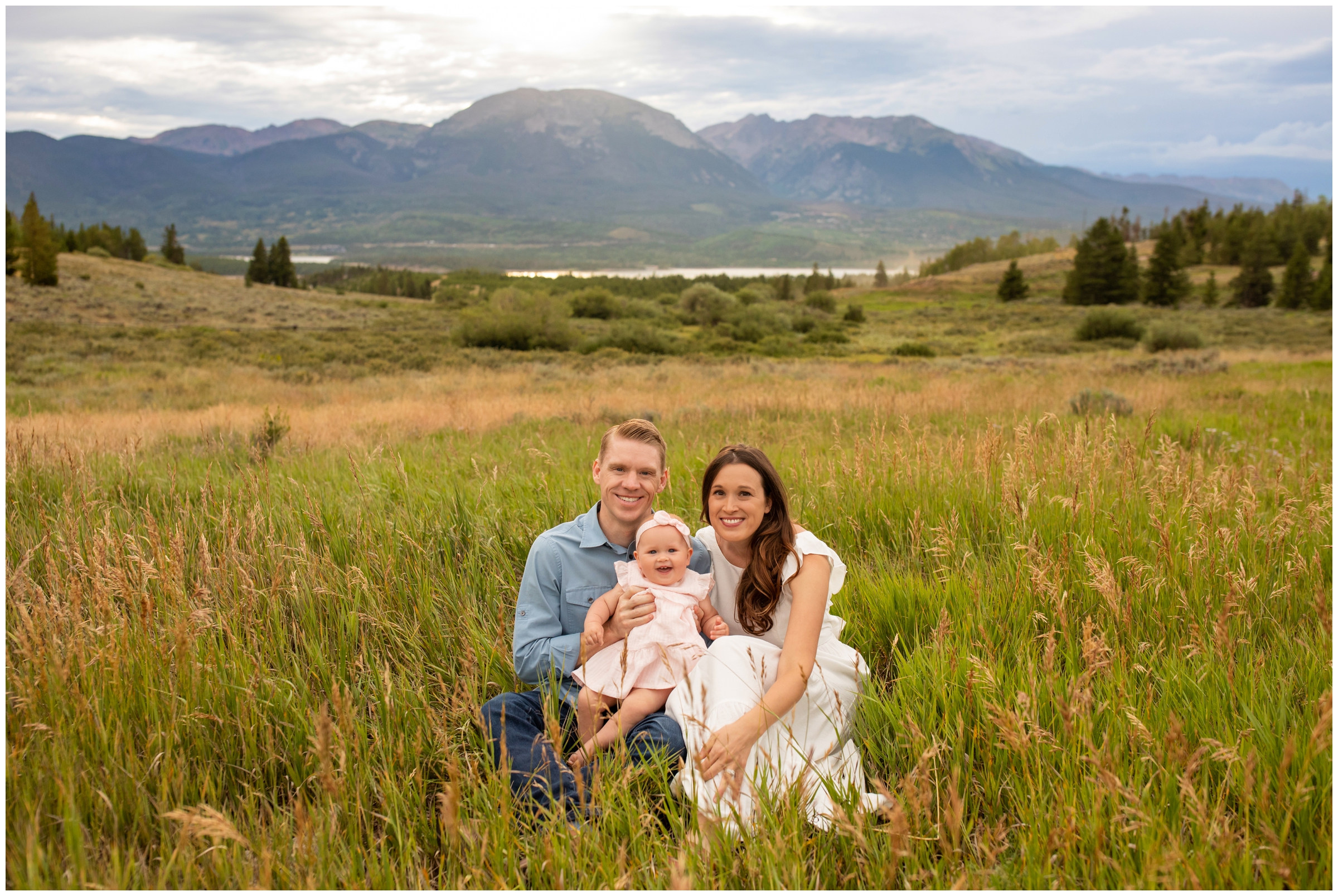 family of three sitting in grassy field during Breckenridge Colorado mountain family portraits at Windy Point Campground