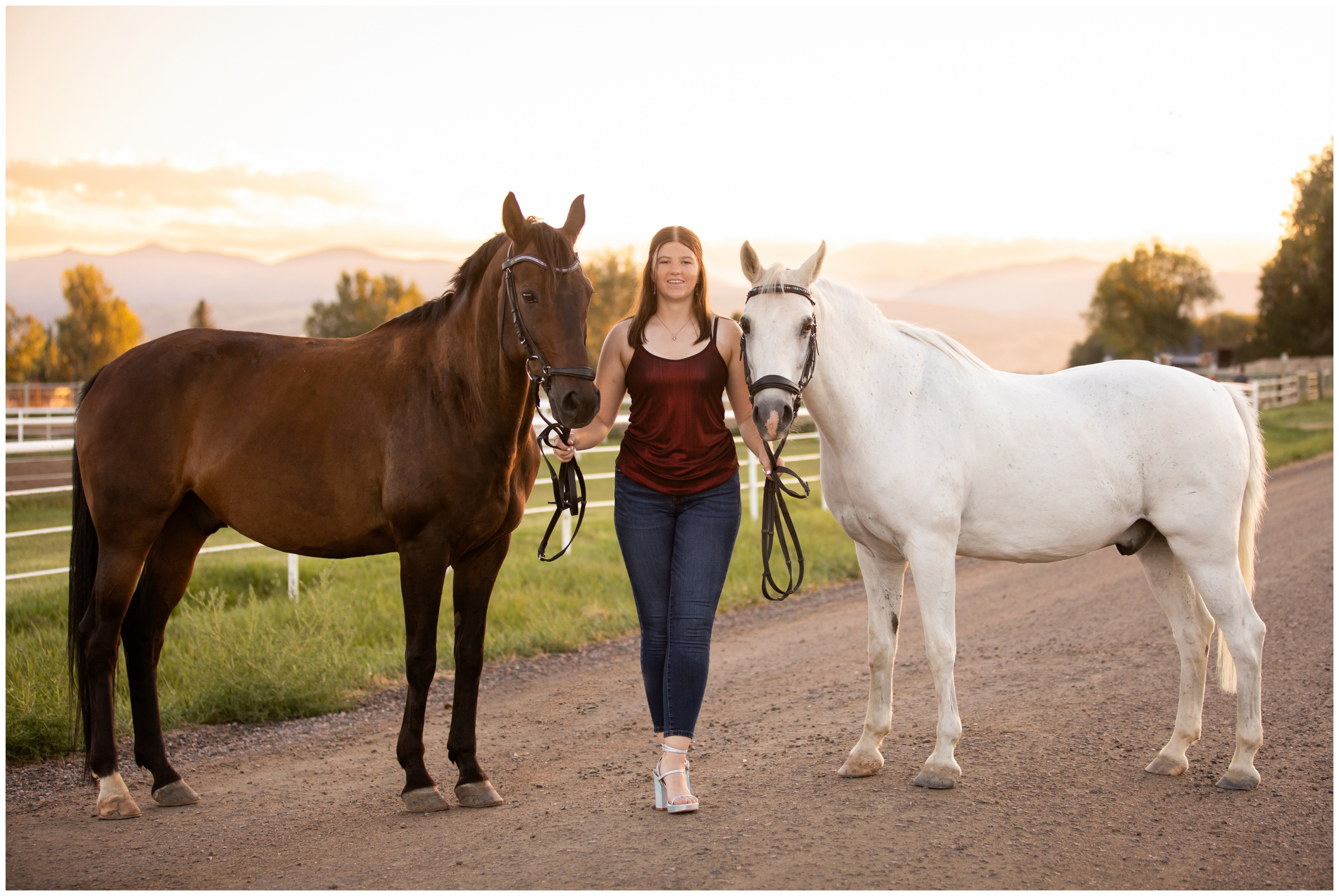 teen posing with horses with mountains in background during Longmont Colorado horse senior portraits
