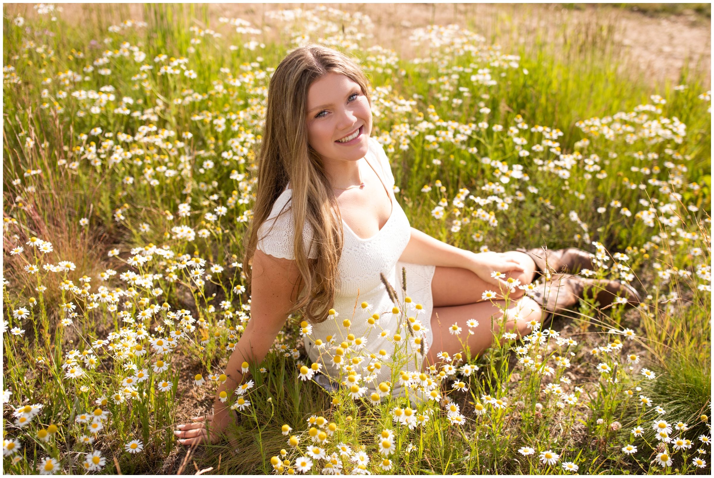 teen sitting in field of white wildflowers during senior pictures in the Colorado mountains 