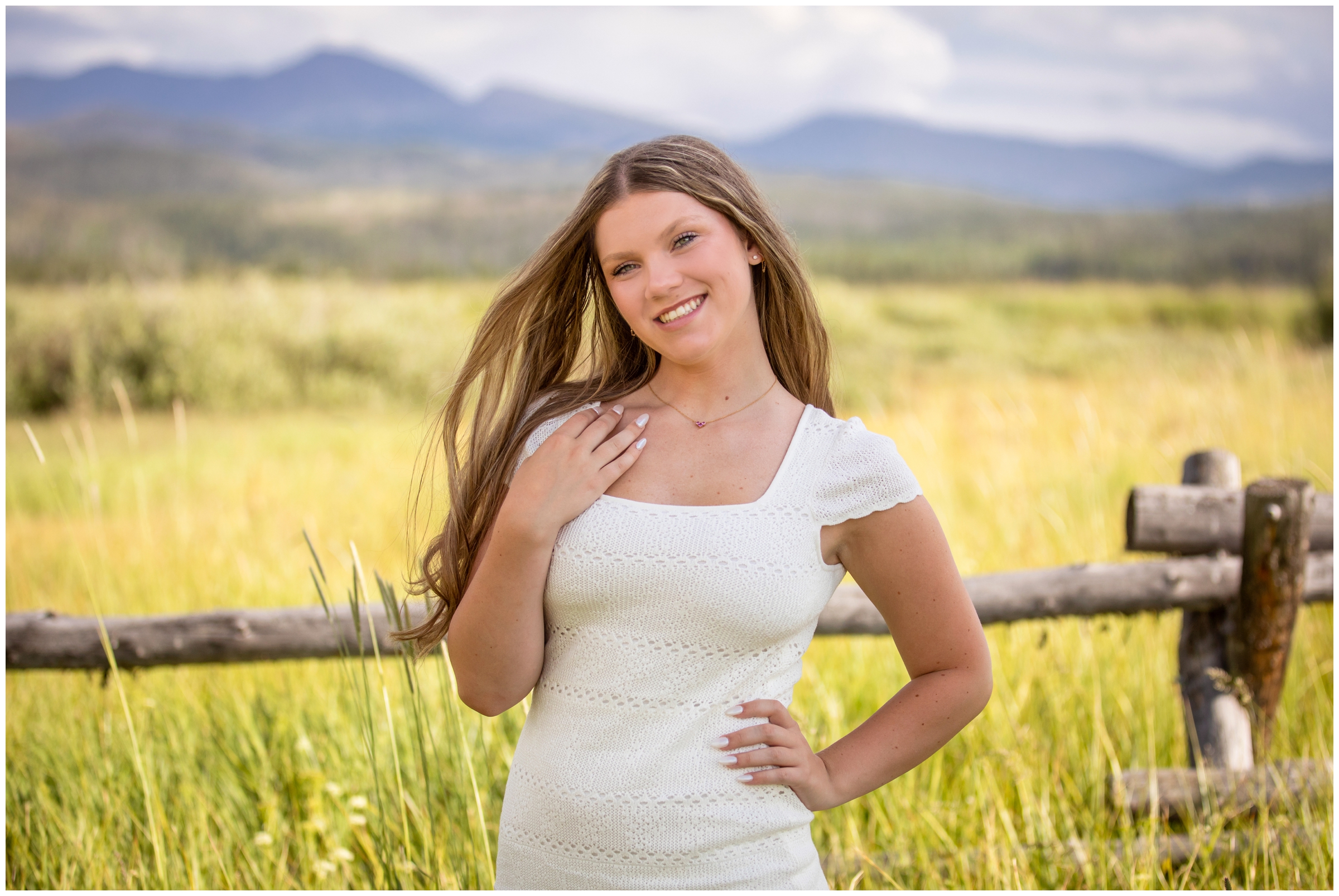 teen posing in a field with mountains in background during Winter Park Colorado senior pictures 