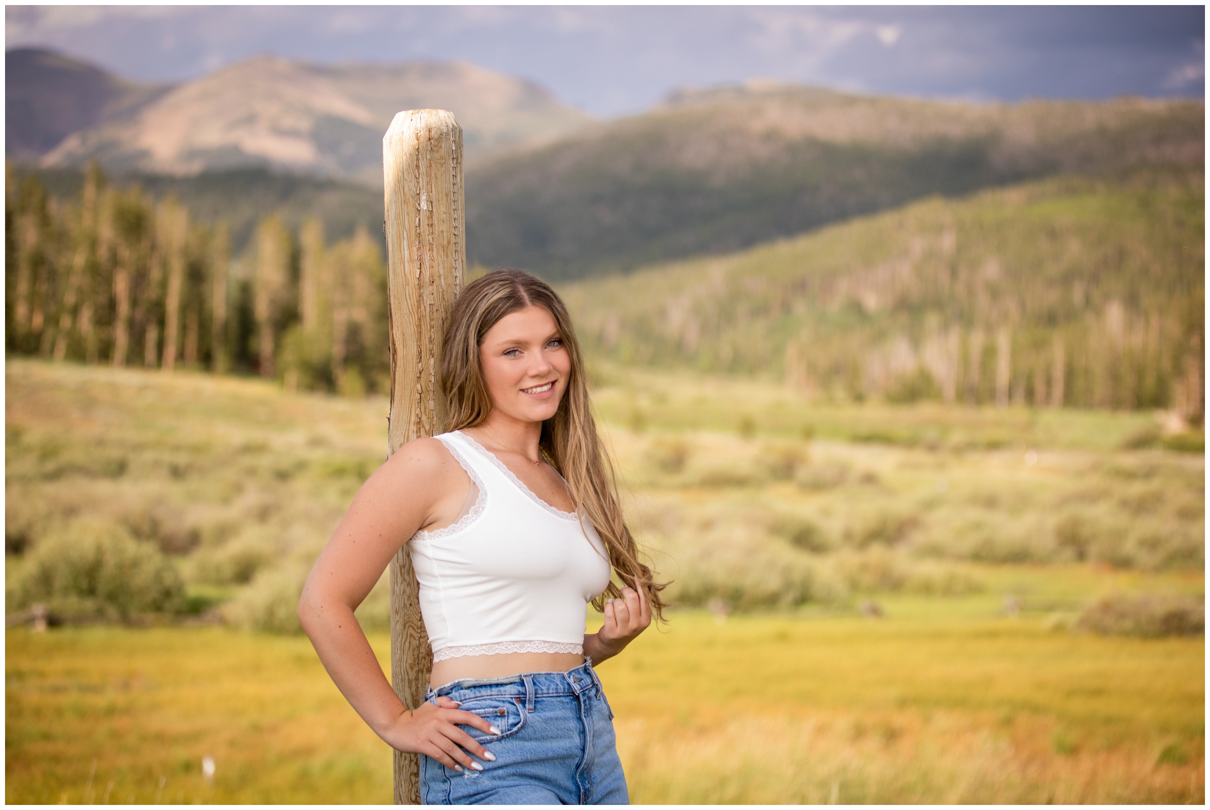 teen leaning against a wooden fence during Colorado mountain senior pictures in Winter Park 