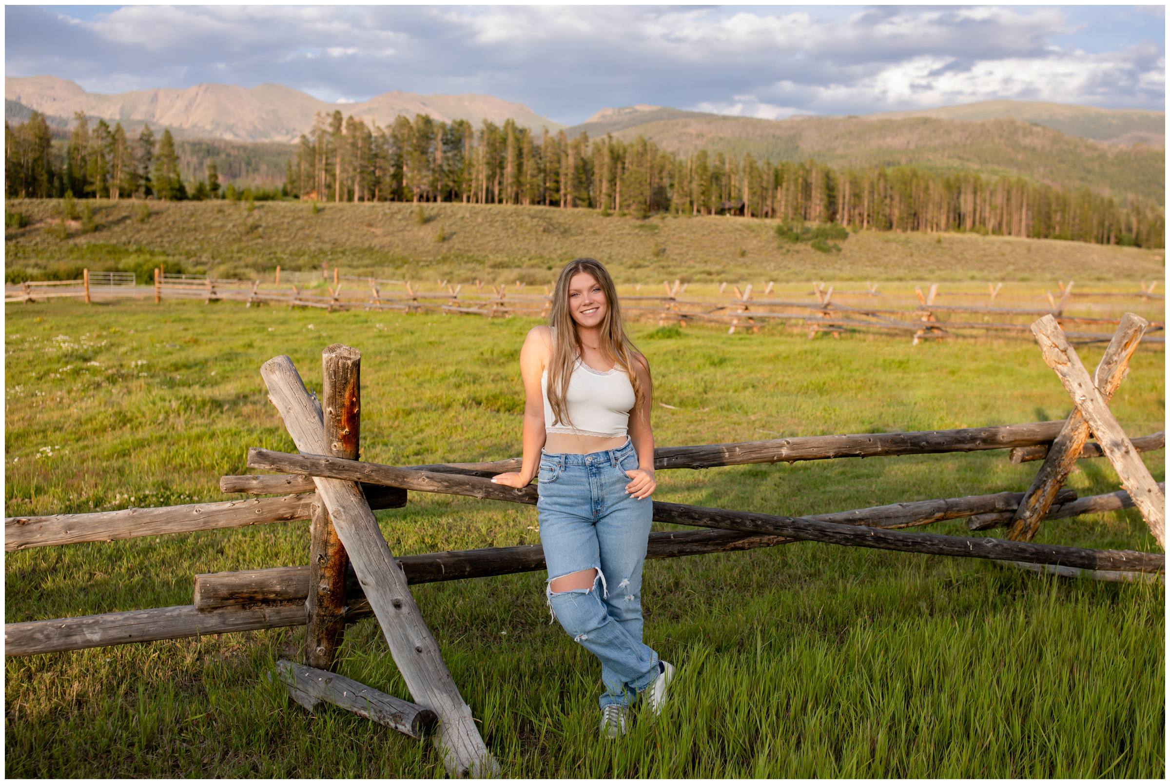 teen leaning on wooden fence during high school graduation pictures at Devil's Thumb in Winter Park CO