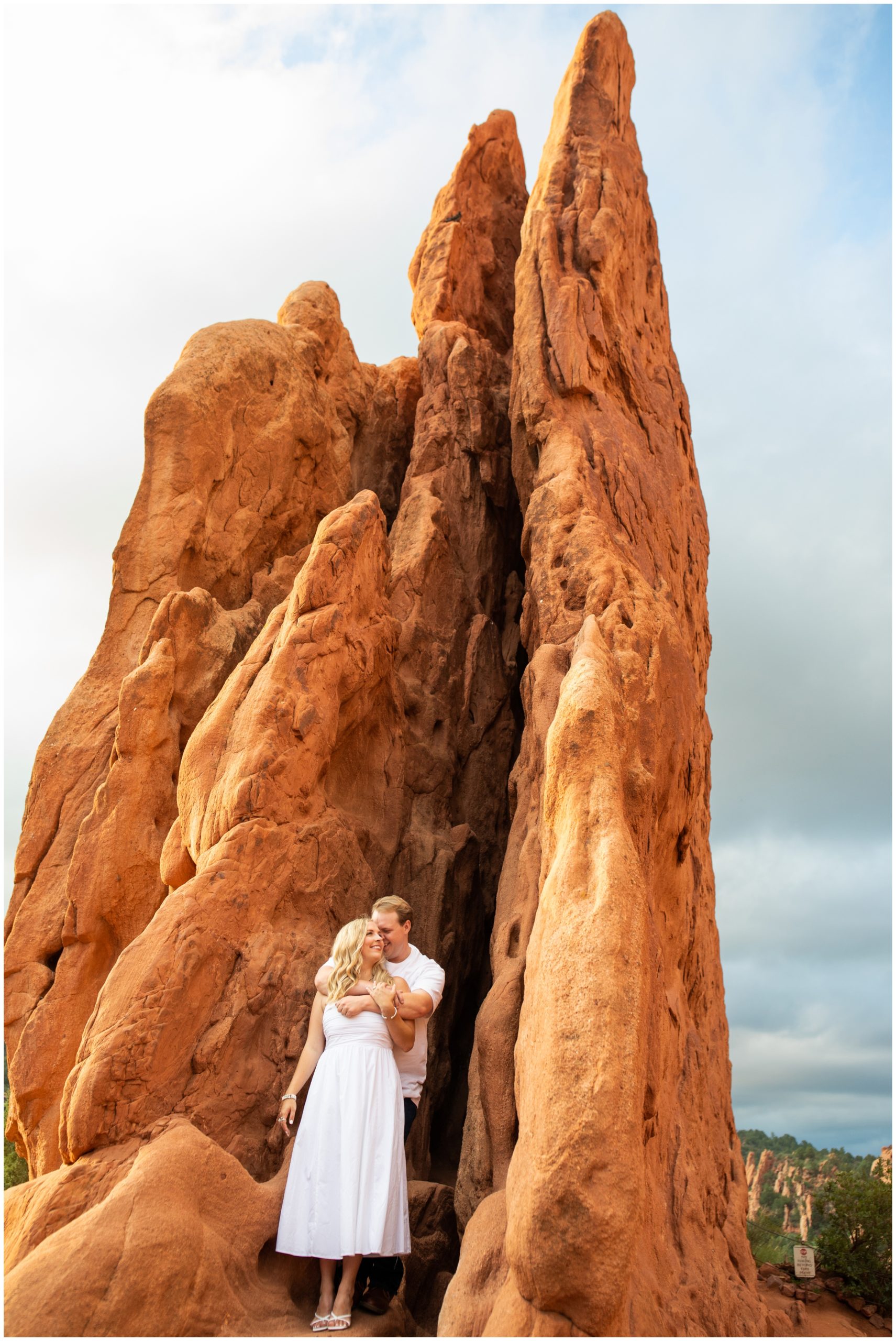 couple embracing beneath red rock formations during Colorado Springs engagement photos at Garden of the Gods