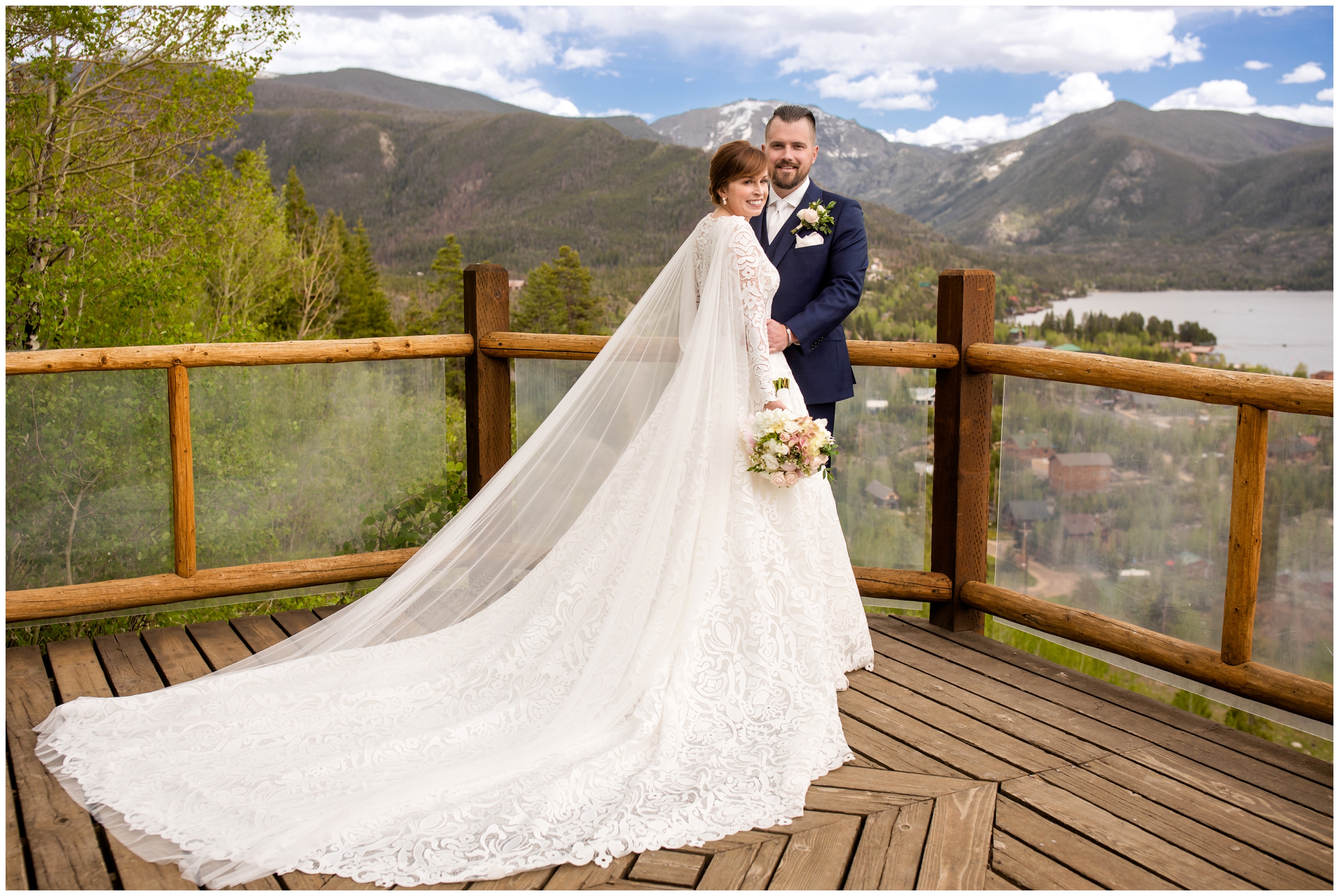 couple posing on wooden deck with mountains in background during Grand Lake Lodge wedding photos in the Colorado mountains 