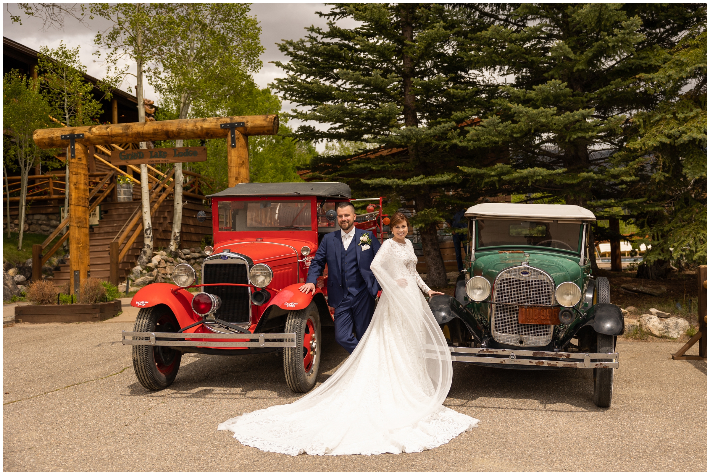 couple posing in front of vintage cars at Grand Lake Lodge wedding in the Colorado mountains 