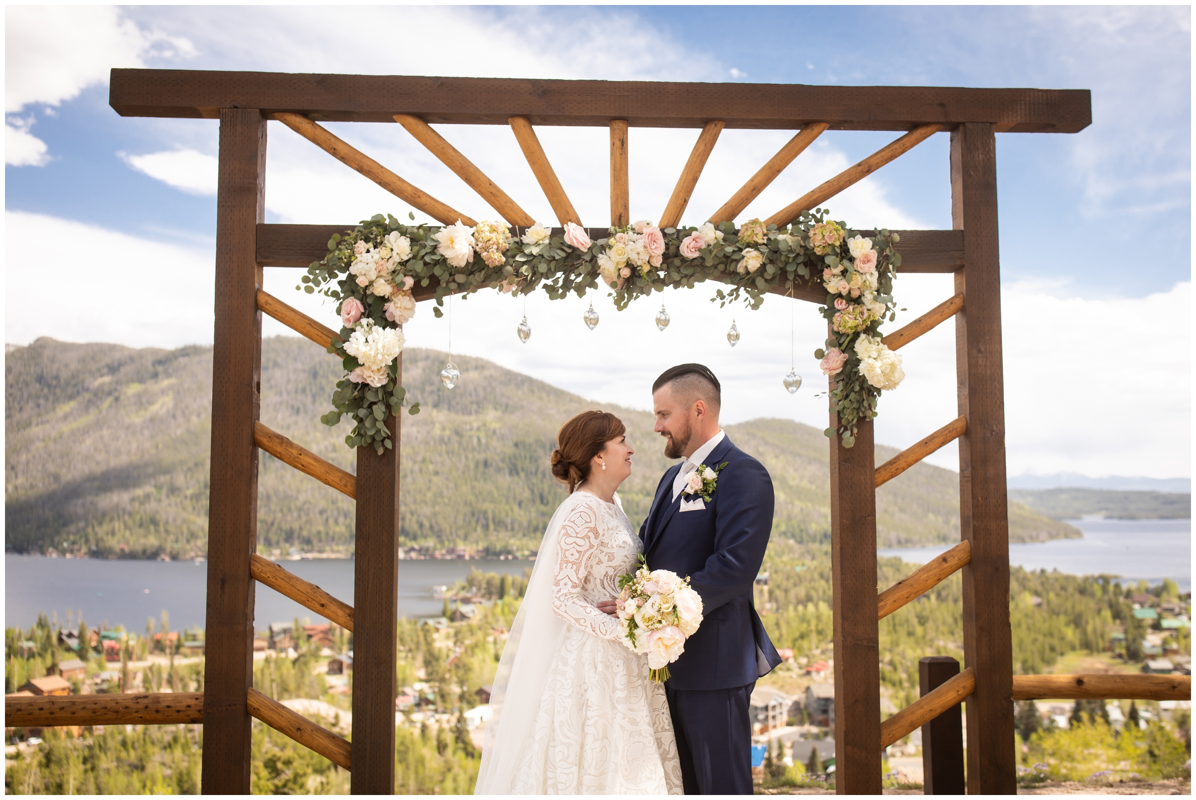 couple posing under wooden arbor at Grand Lake Lodge wedding by Colorado mountain wedding photographer Plum Pretty Photography