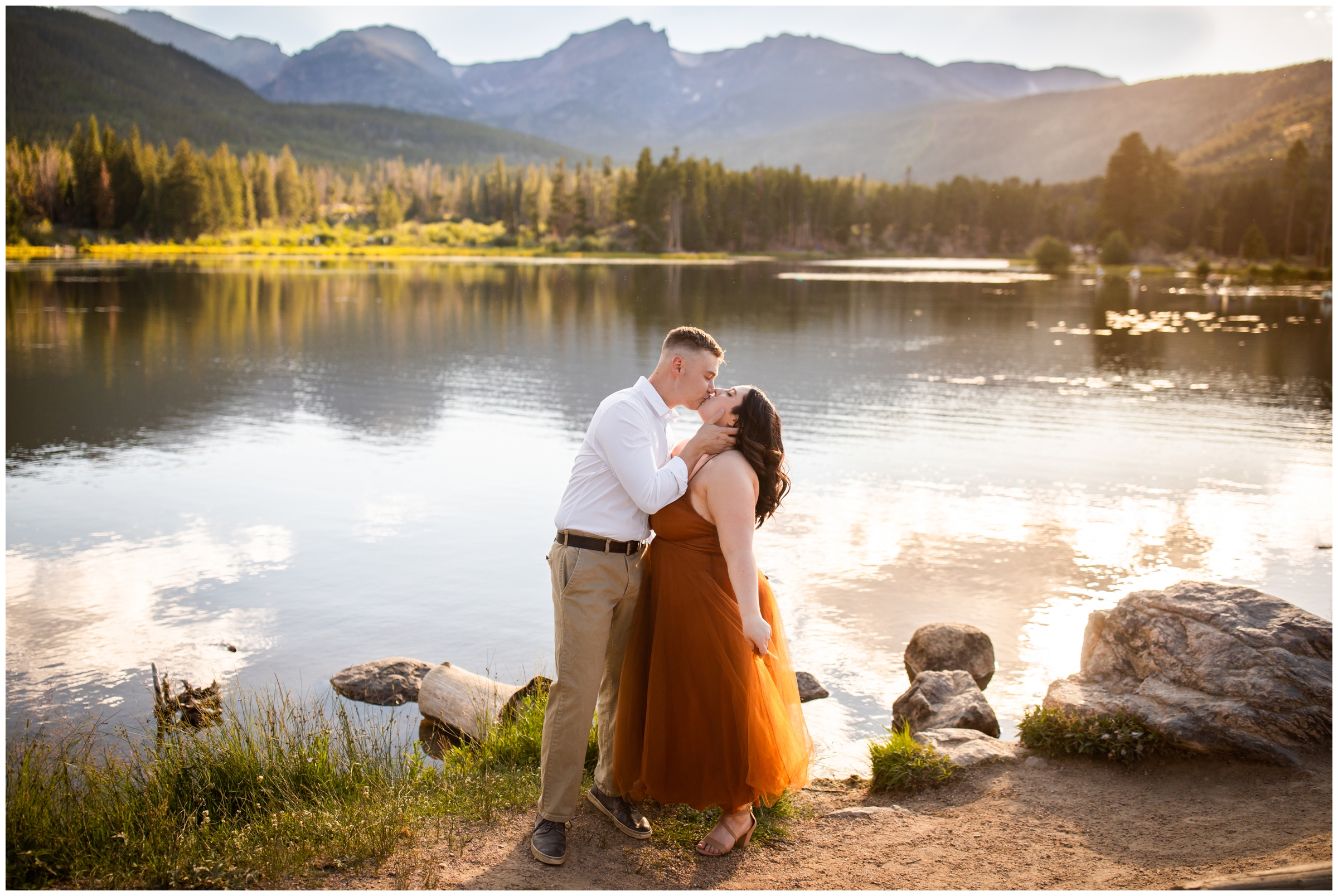 couple kissing with the mountains in background during Colorado engagement photography session at Sprague Lake in RMNP