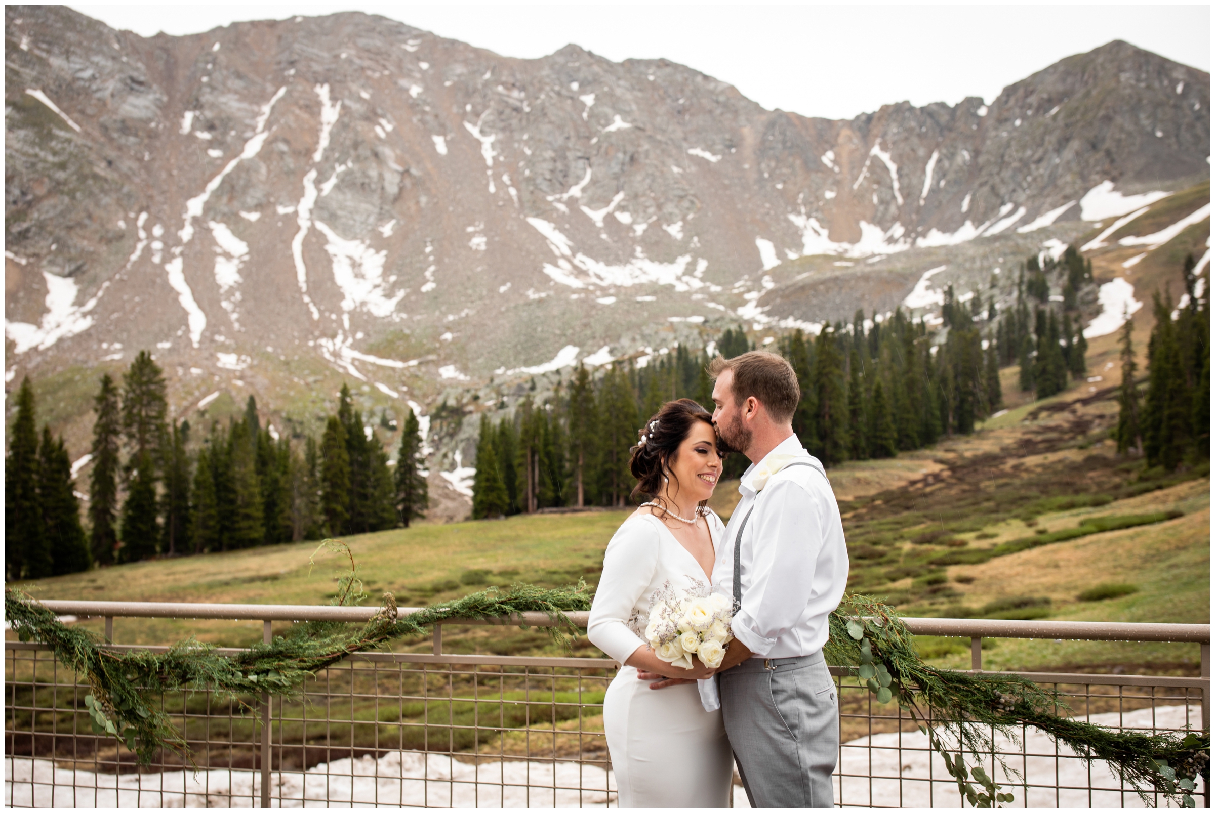 groom kissing bride's forehead during romantic wedding portraits at Arapahoe Basin in Colorado mountains 