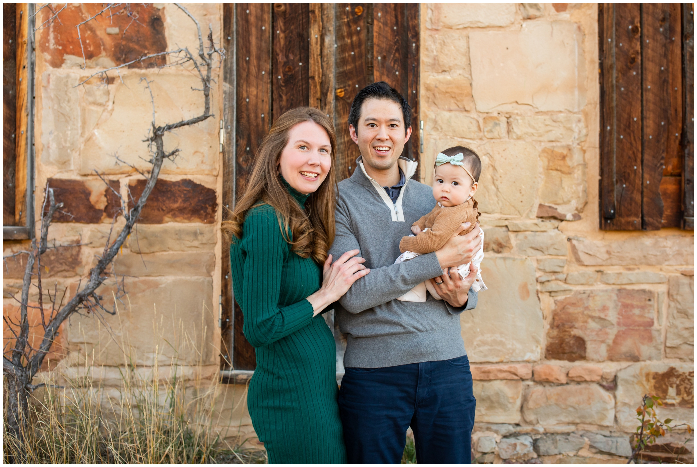 family posing in front of rustic stone building at South Mesa during Colorado family photography session 