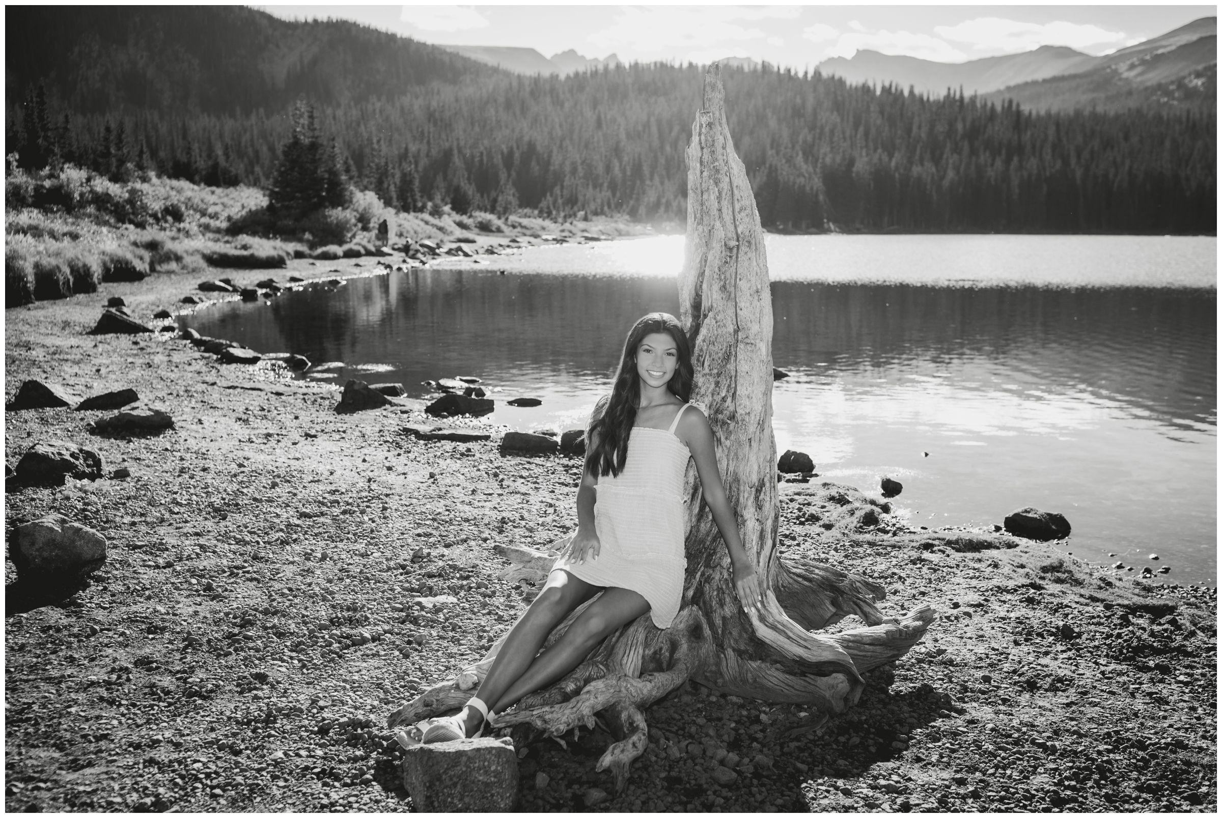 teen girl leaning on driftwood at Colorado lake senior photography session 