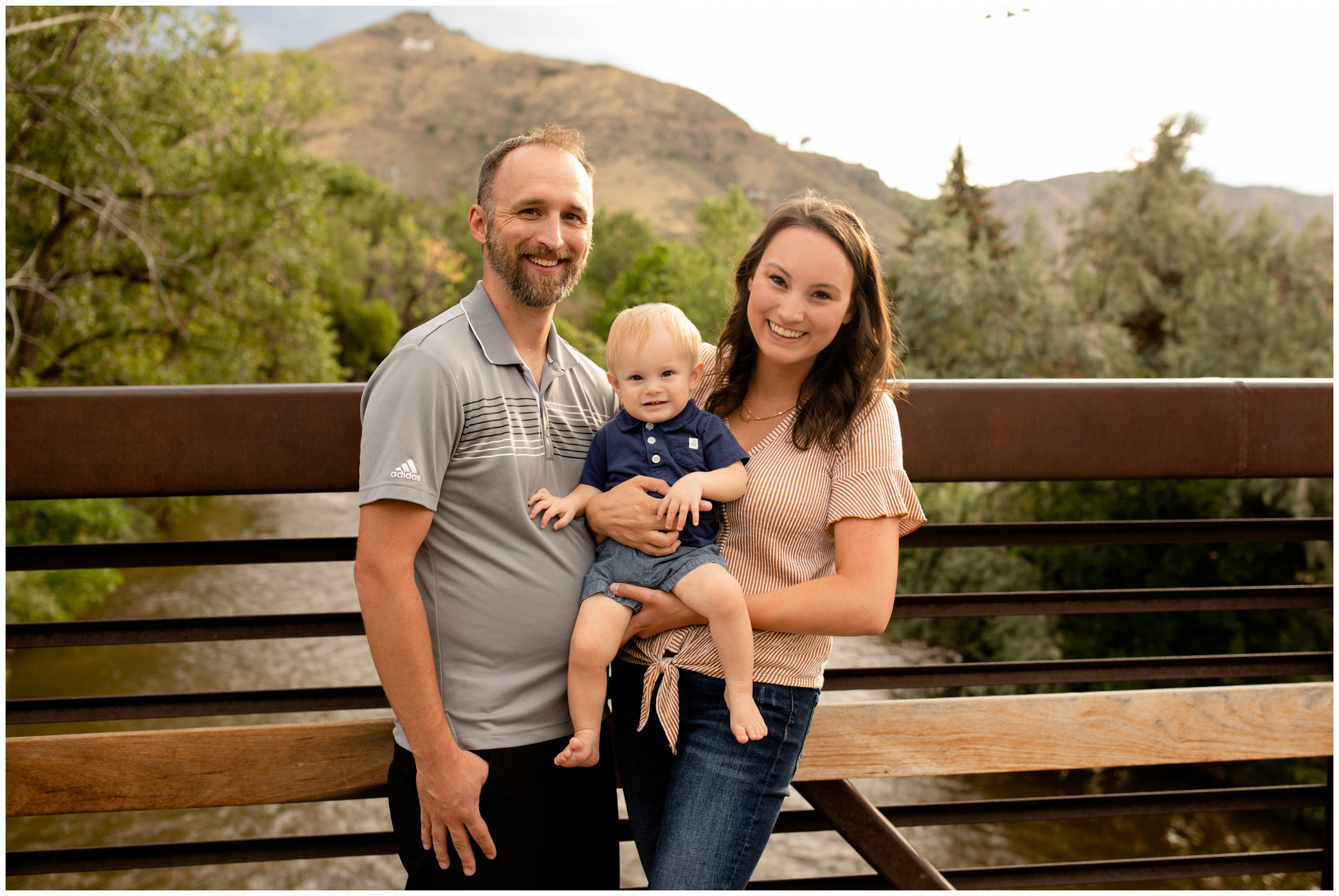 family posing on a bridge with mountains in background during Golden Colorado family photography session 