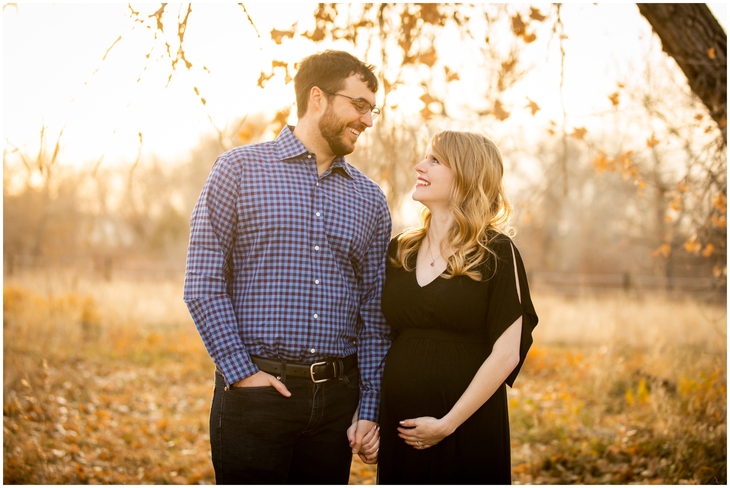 couple posing in field of long grasses during Centennial CO pregnancy session