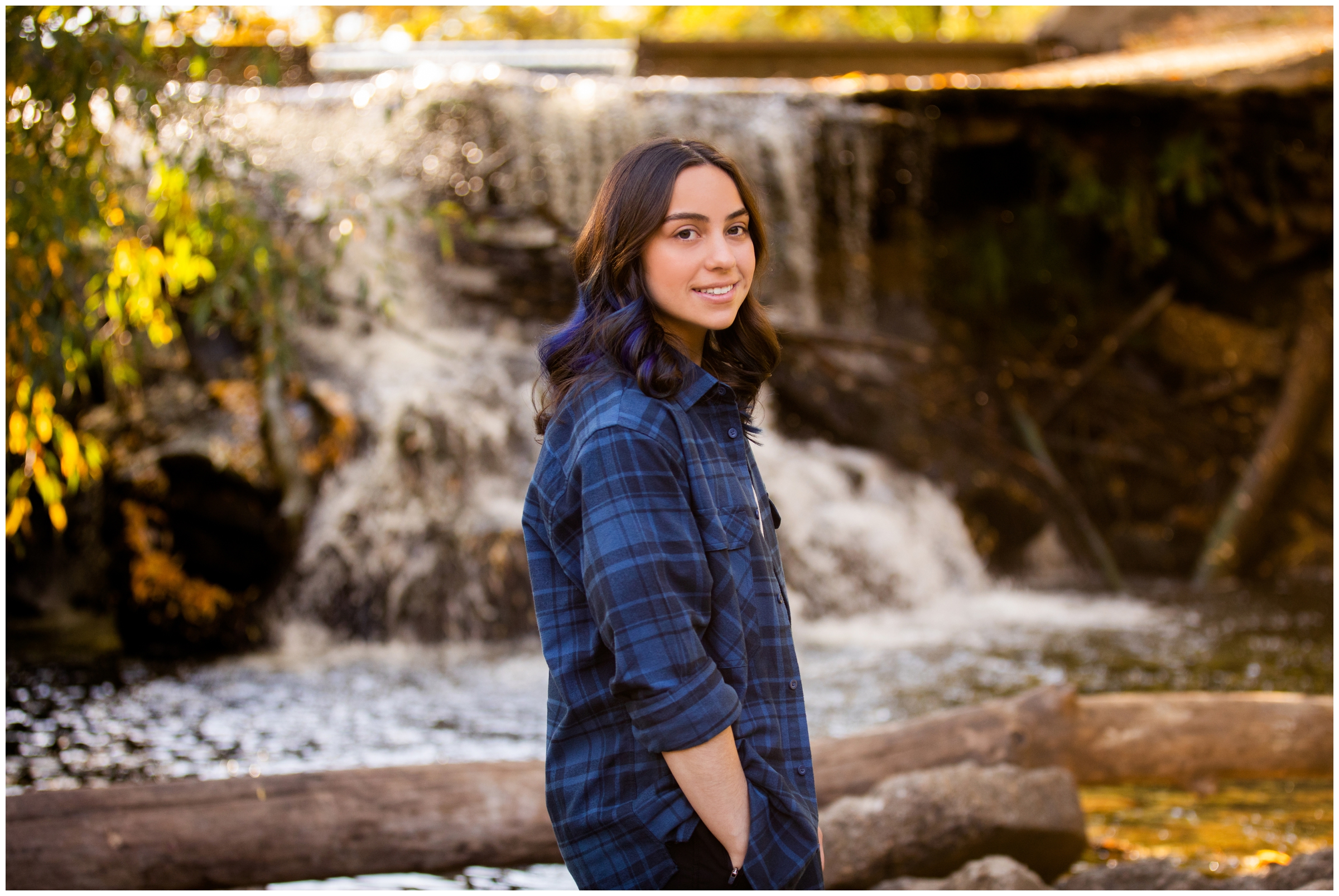 teen posing in front of waterfall during Longmont graduation photography session at Golden Ponds