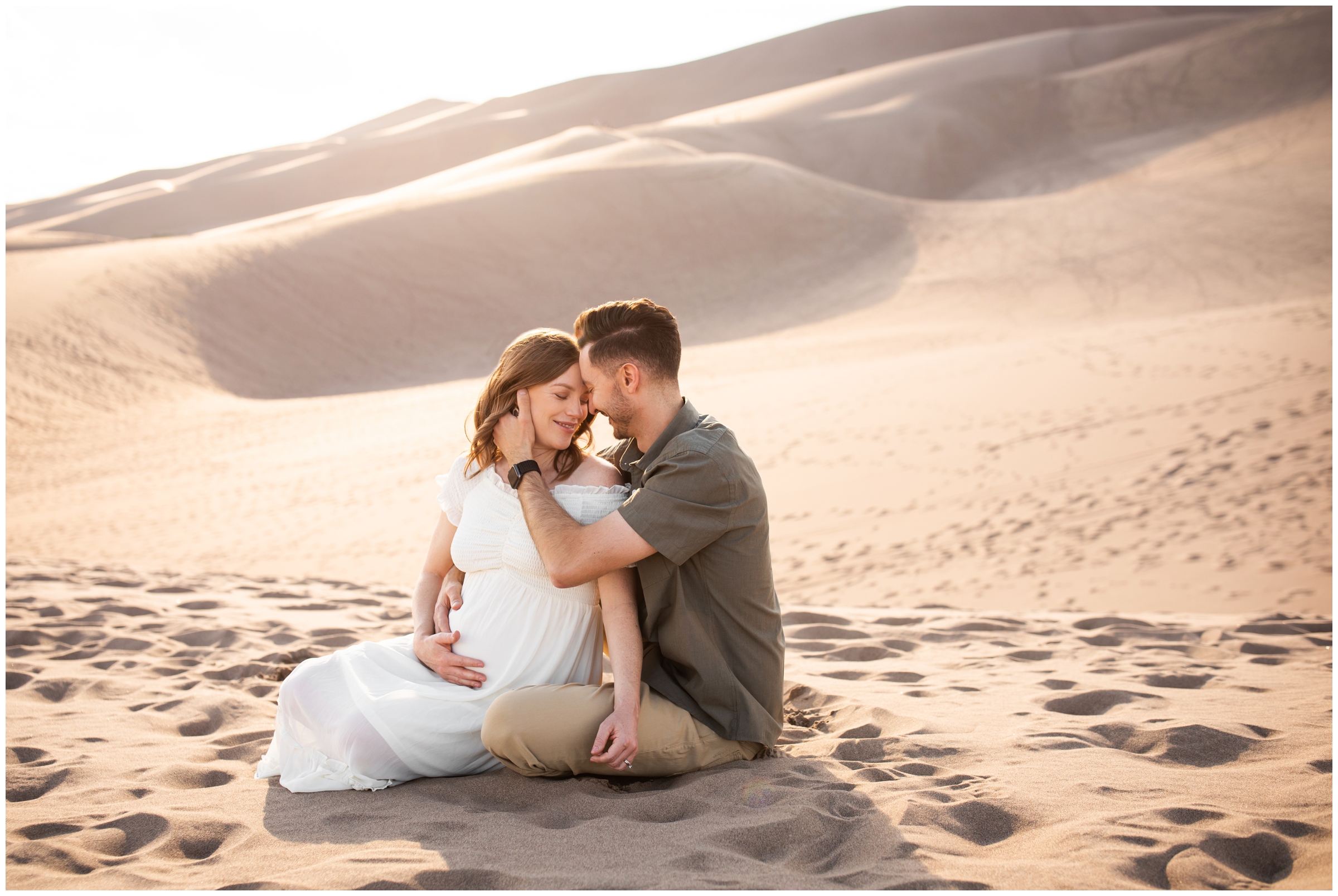 couple sitting in the sand during Colorado maternity portraits at the Great Sand Dunes National Park 
