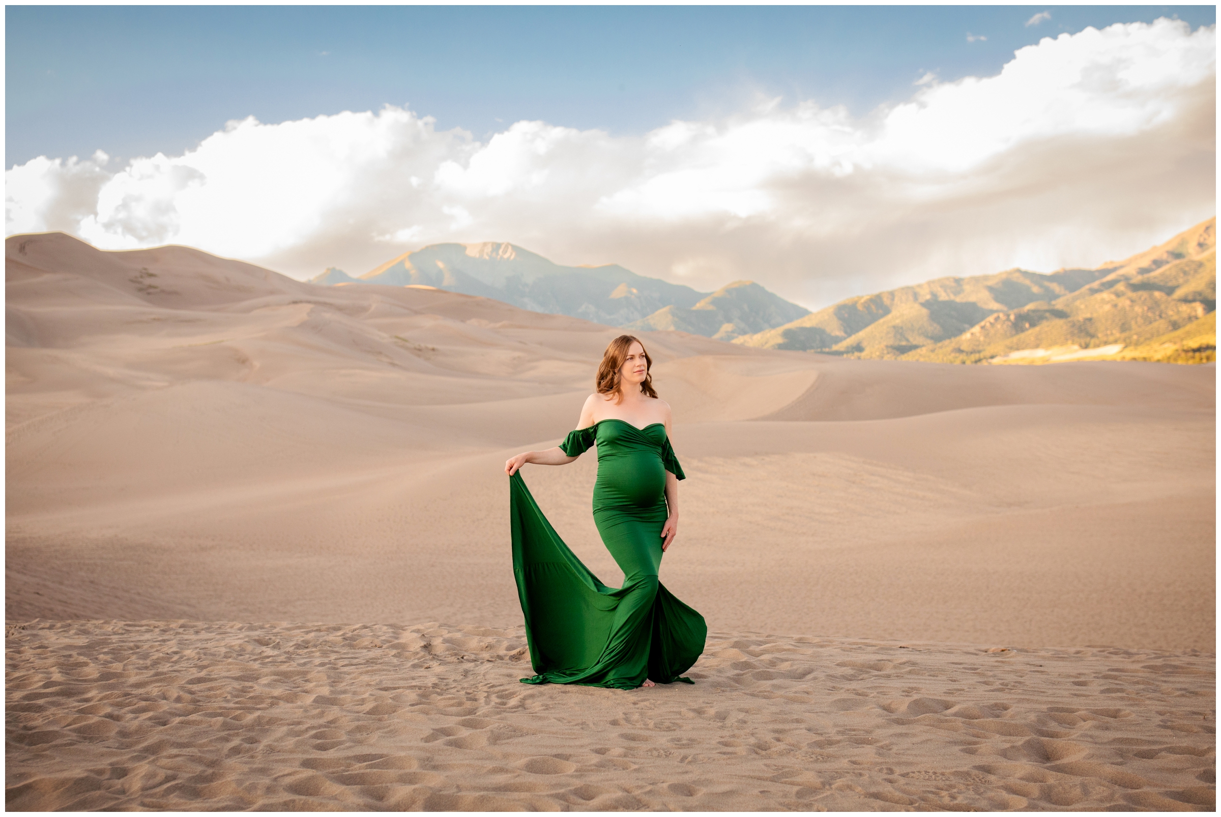 woman in green maternity dress posing at the Great Sand Dunes during unique maternity pictures in Colorado