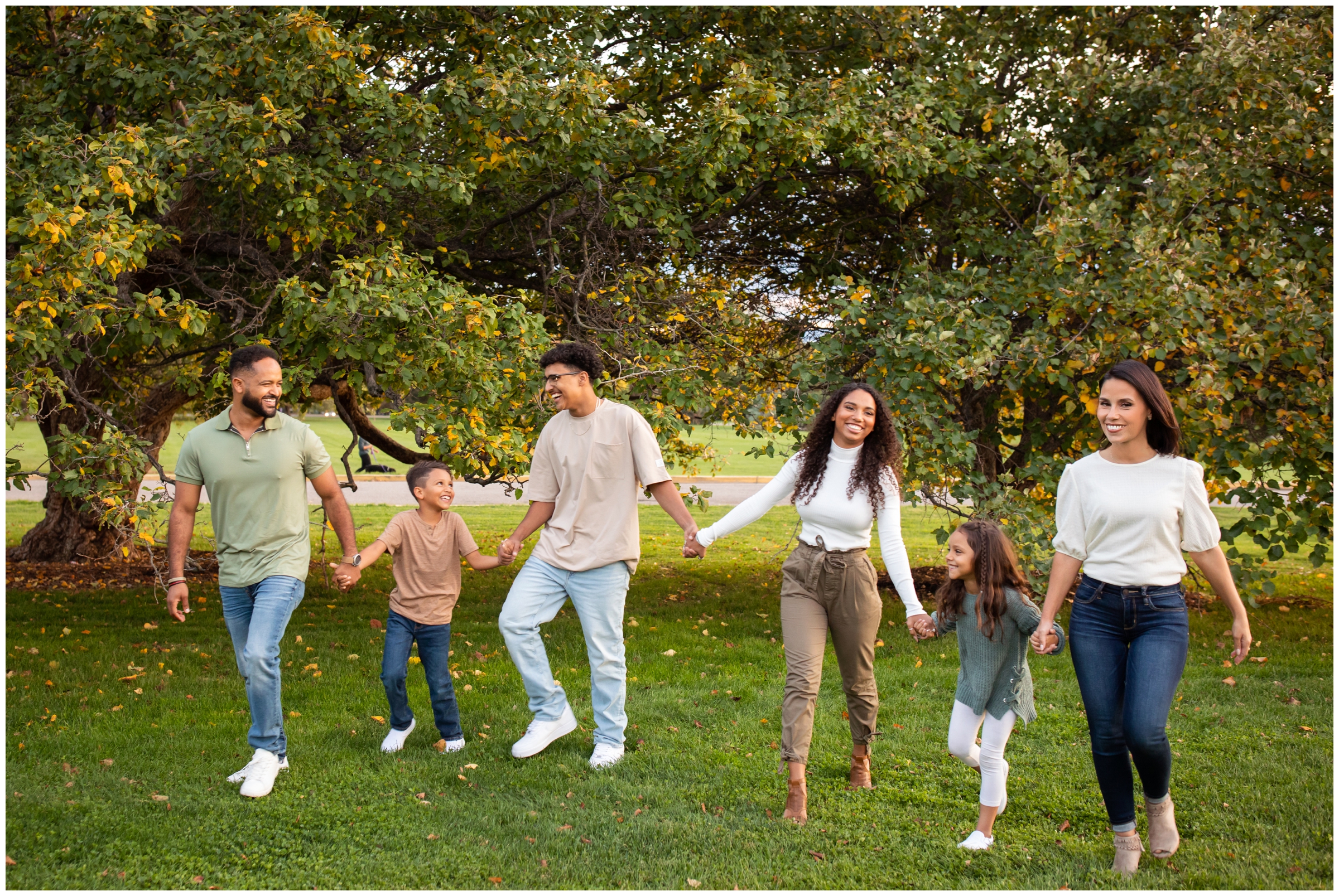 family of six holding hands and walking during Denver Colorado candid family photos at Cheesman Park 