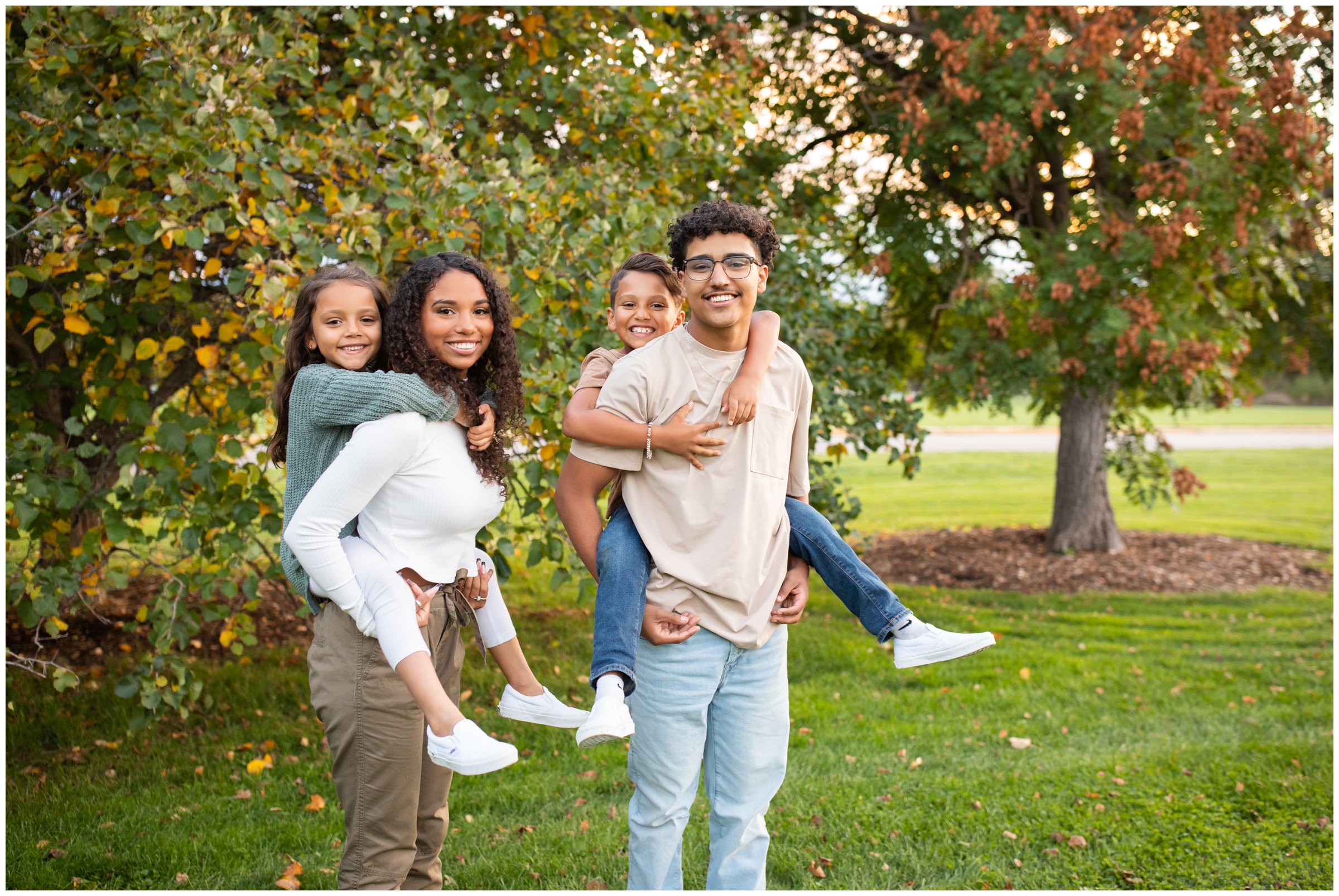 older siblings giving younger siblings piggy back rides during fall family photography session in Denver 
