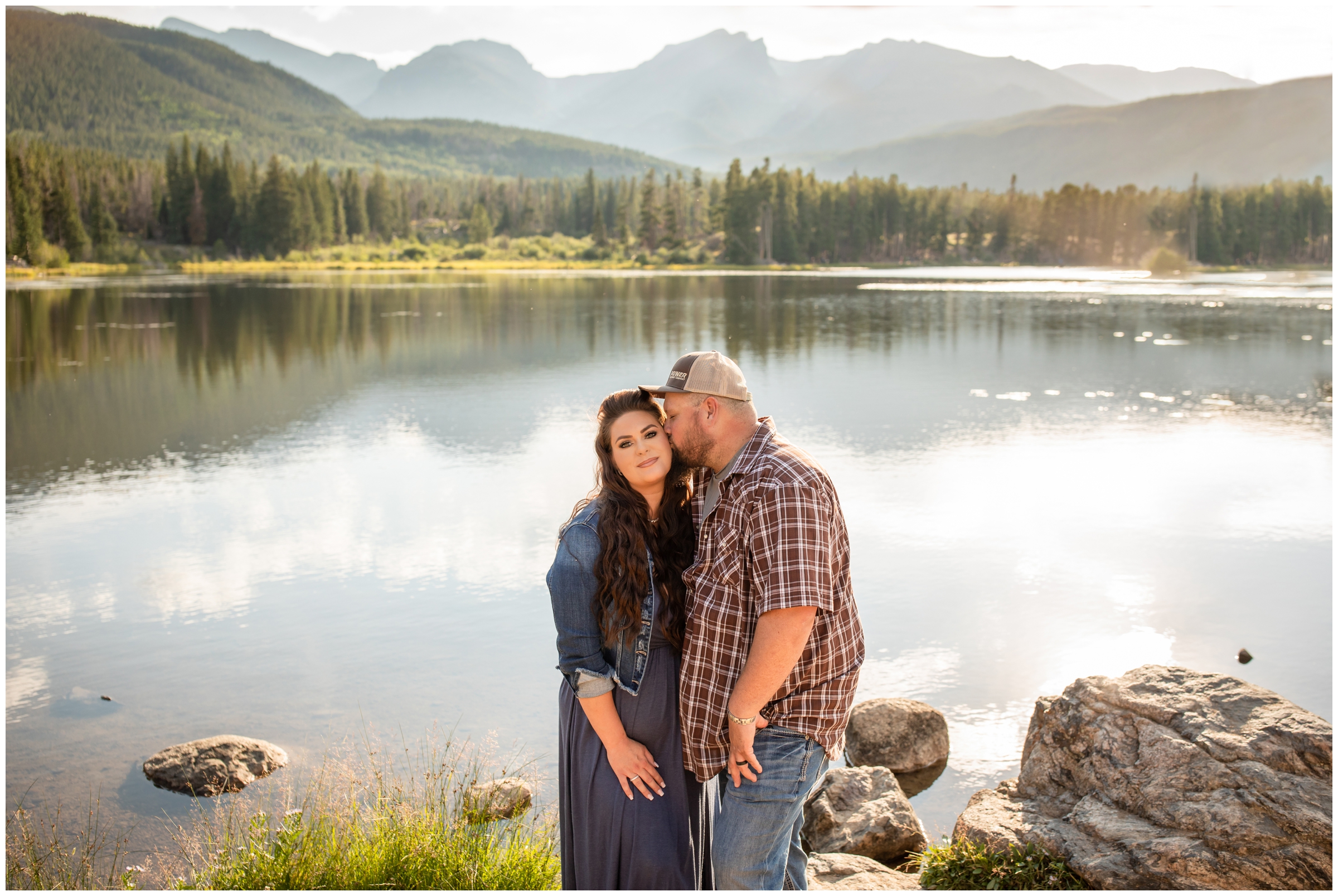 couple kissing in front of mountains during Estes Park Colorado anniversary photo shoot at Sprague Lake 