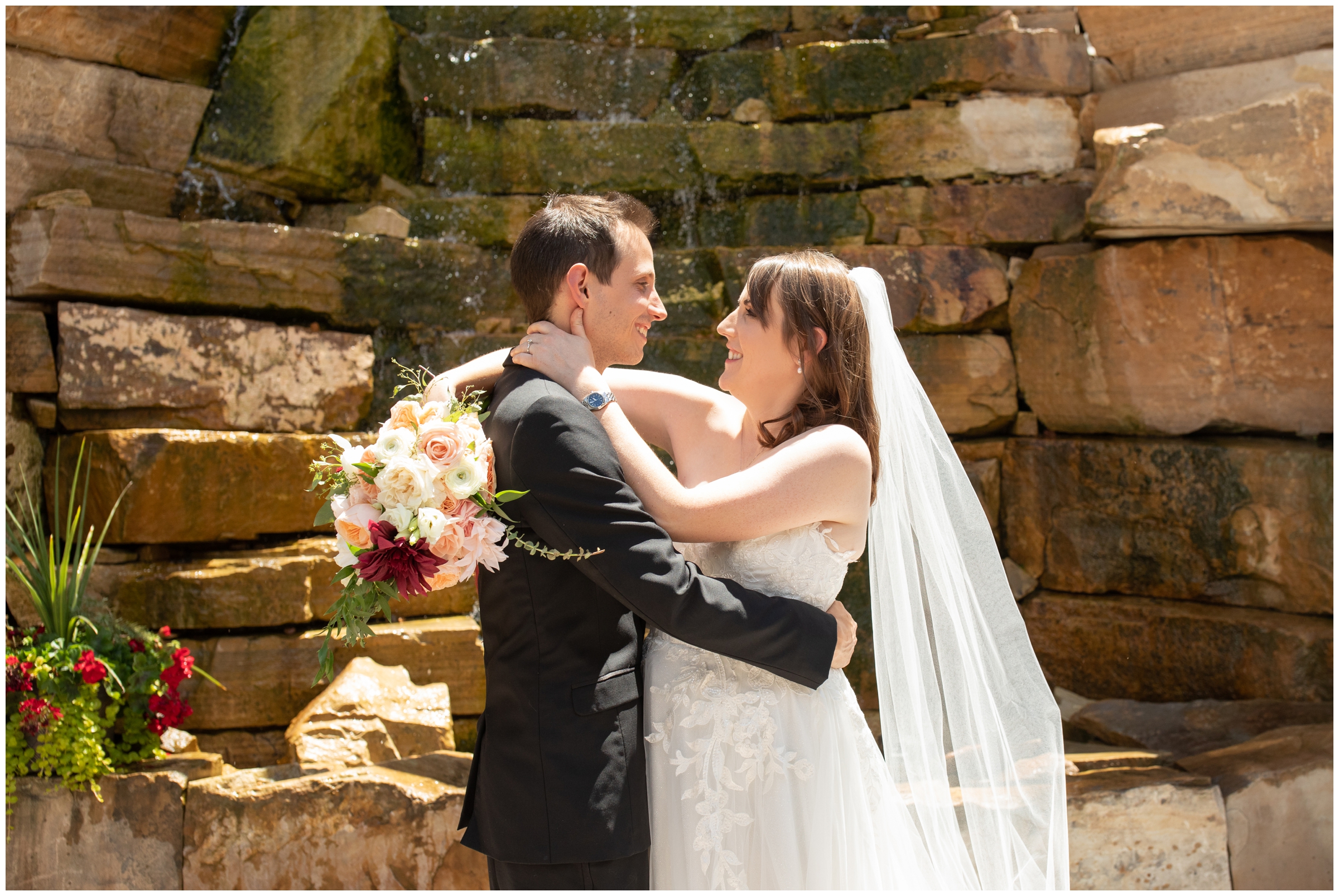 bride and groom posing in front of rock wall water feature at Estes Park inn at fall river wedding photos