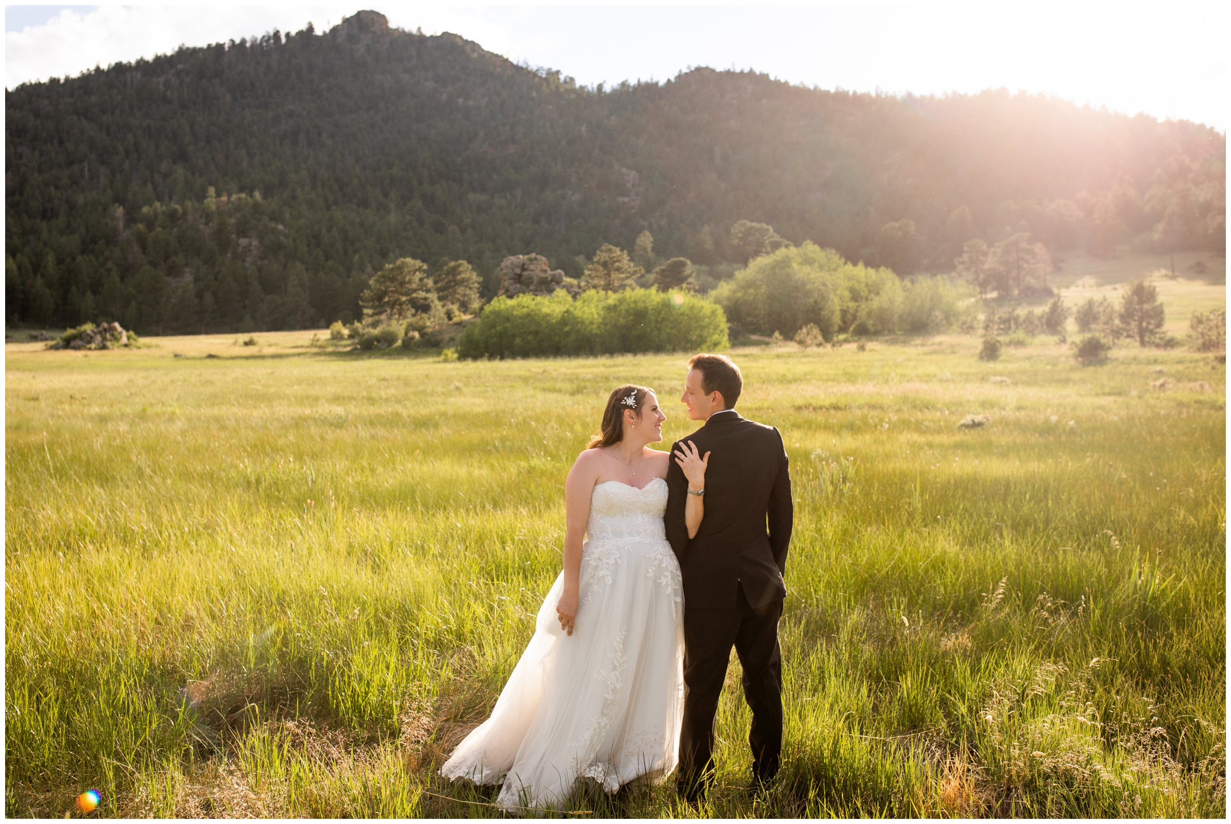 couple posing in open field with mountains in background during Estes Park Colorado wedding portraits at Hermit Park