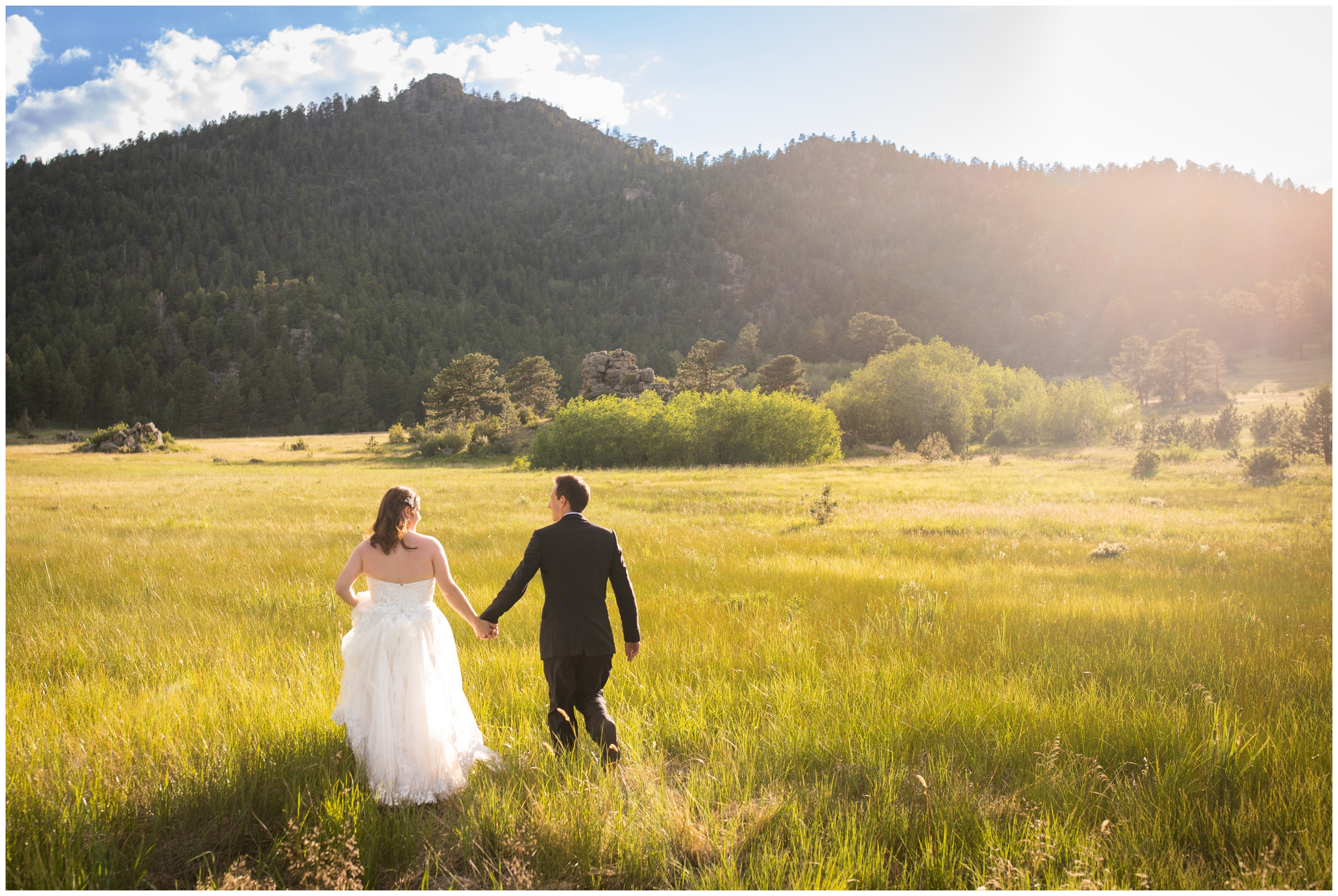 couple holding hands and walking through a sunny open field during intimate wedding pictures at Hermit Park in Estes Park Colorado 