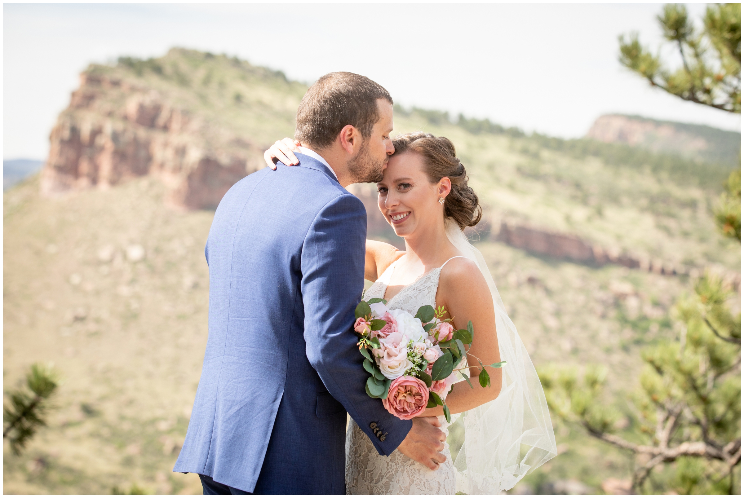 groom kissing bride's forehead with mountains in background during Lyons Colorado wedding picture 